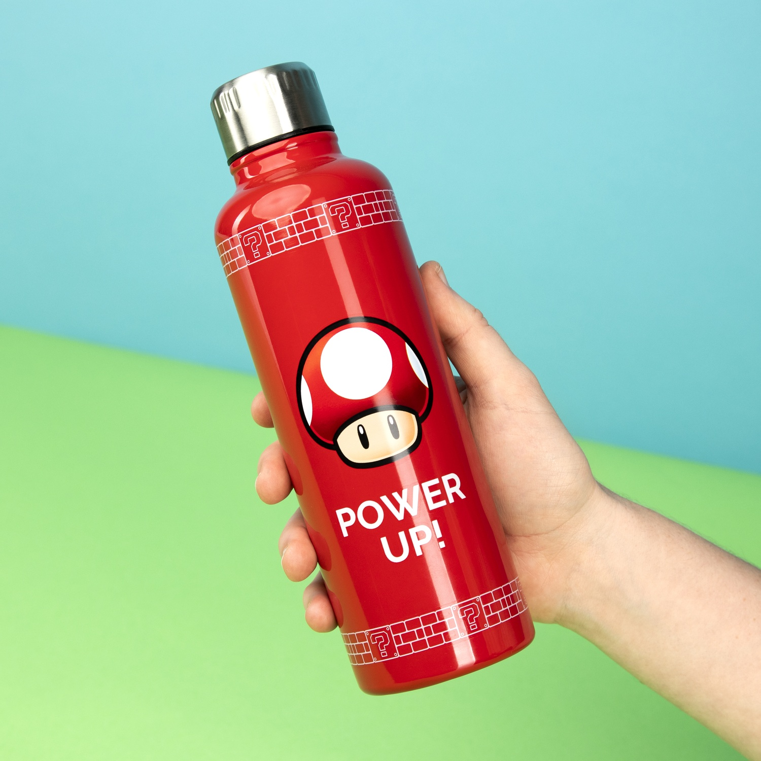 A red water bottle with a mushroom design, held by a hand.