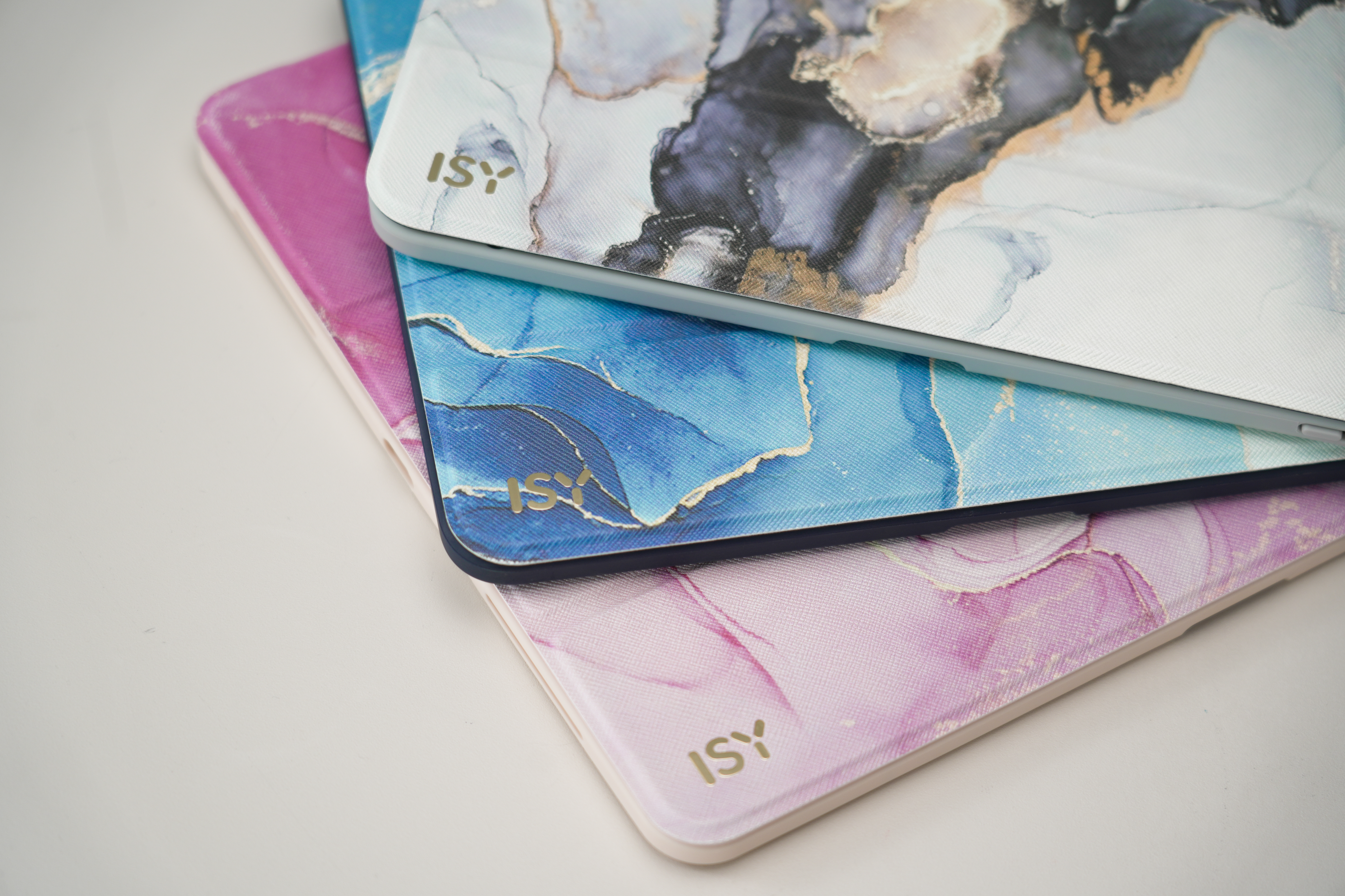 Drei Tablet-Hüllen mit Marmormustern in Rosa, Blau und Weiß.