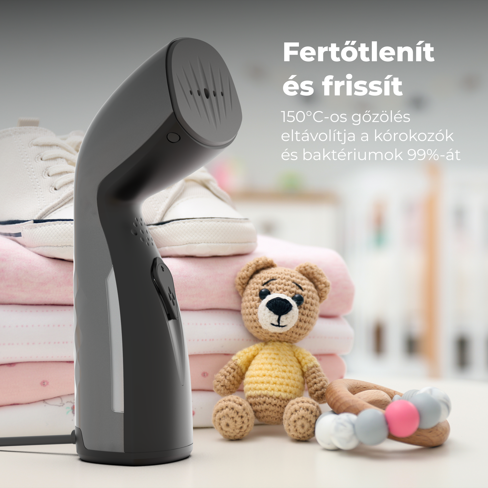Egy fekete gőzölő, egy mackóval, ruhákkal és egy fa játékkel az asztalon. Szöveg: „Fertőtleníteni és frissíteni”.