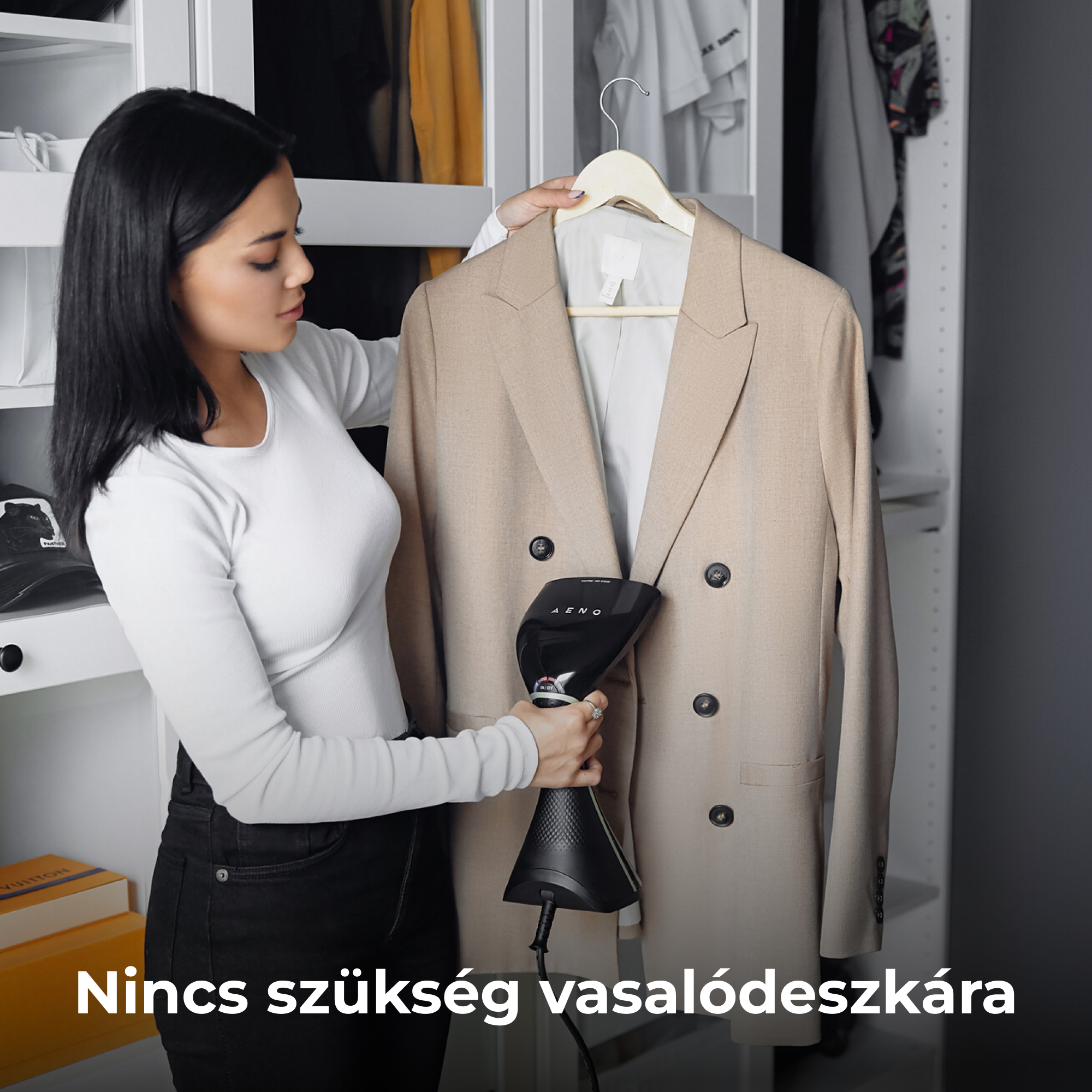 Nő kézi gőzölőt használ bézs blézeren. A szekrényben van, fehér felsőt és fekete nadrágot visel.