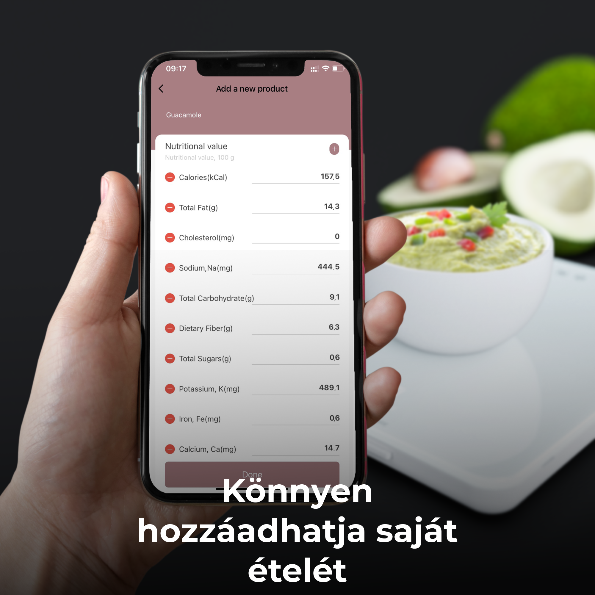 Egy kéz egy telefont tart, guacamole tápértékét mutatja. Fehér tál guacamoléval.