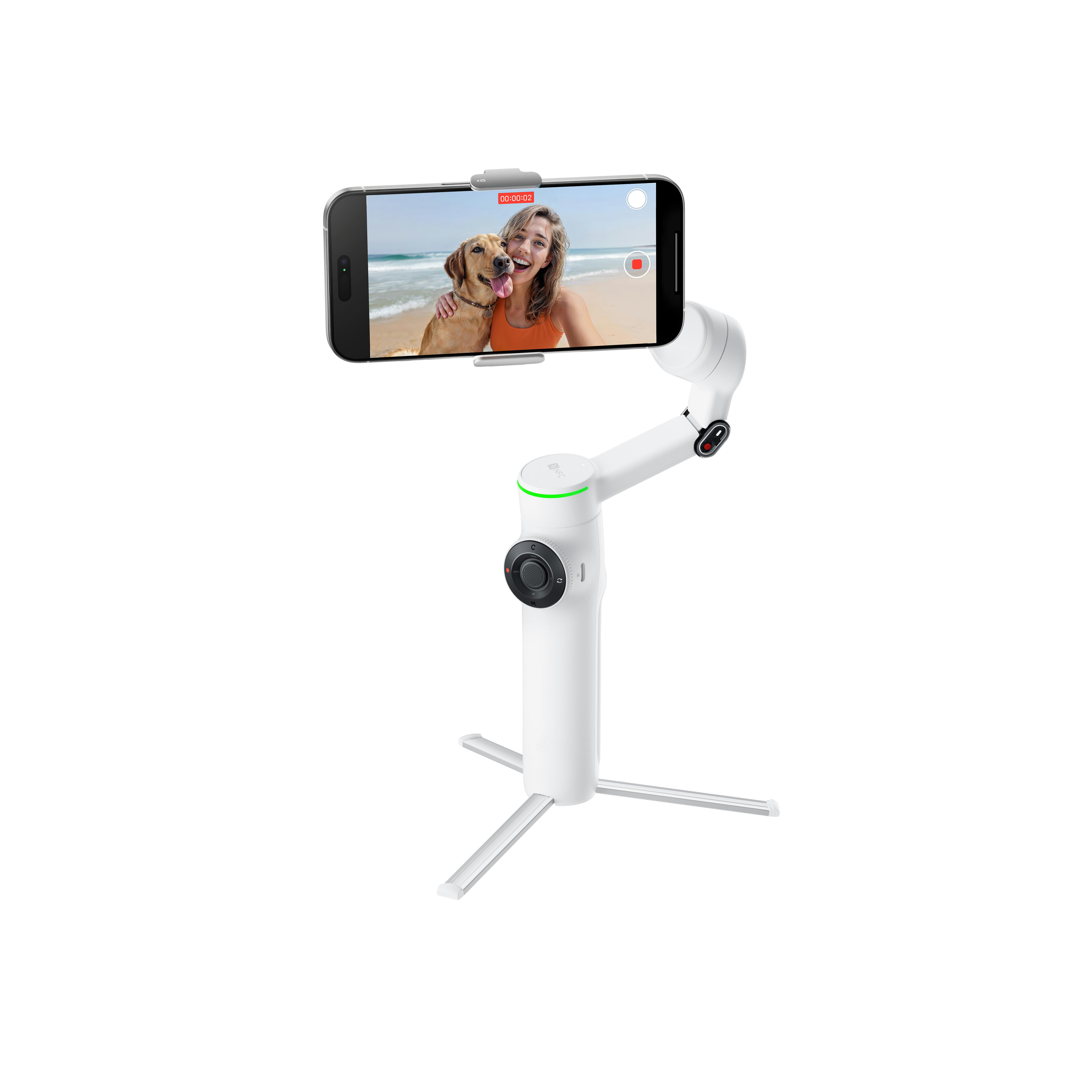 Weißer Telefon-Gimbal, der ein Telefon hält, das eine Frau und einen Hund am Strand zeigt. Es steht auf einer weißen Oberfläche.