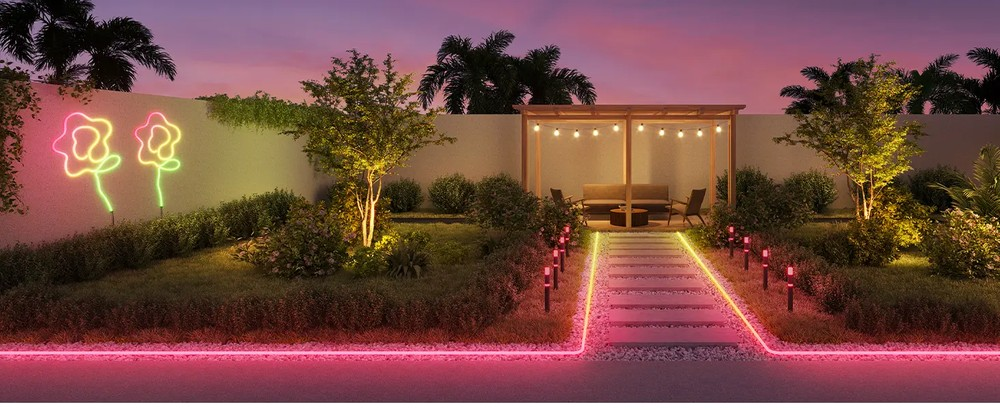 Scena w ogrodzie o zmierzchu z podświetlonymi ścieżkami i neonowymi światłami kwiatowymi.