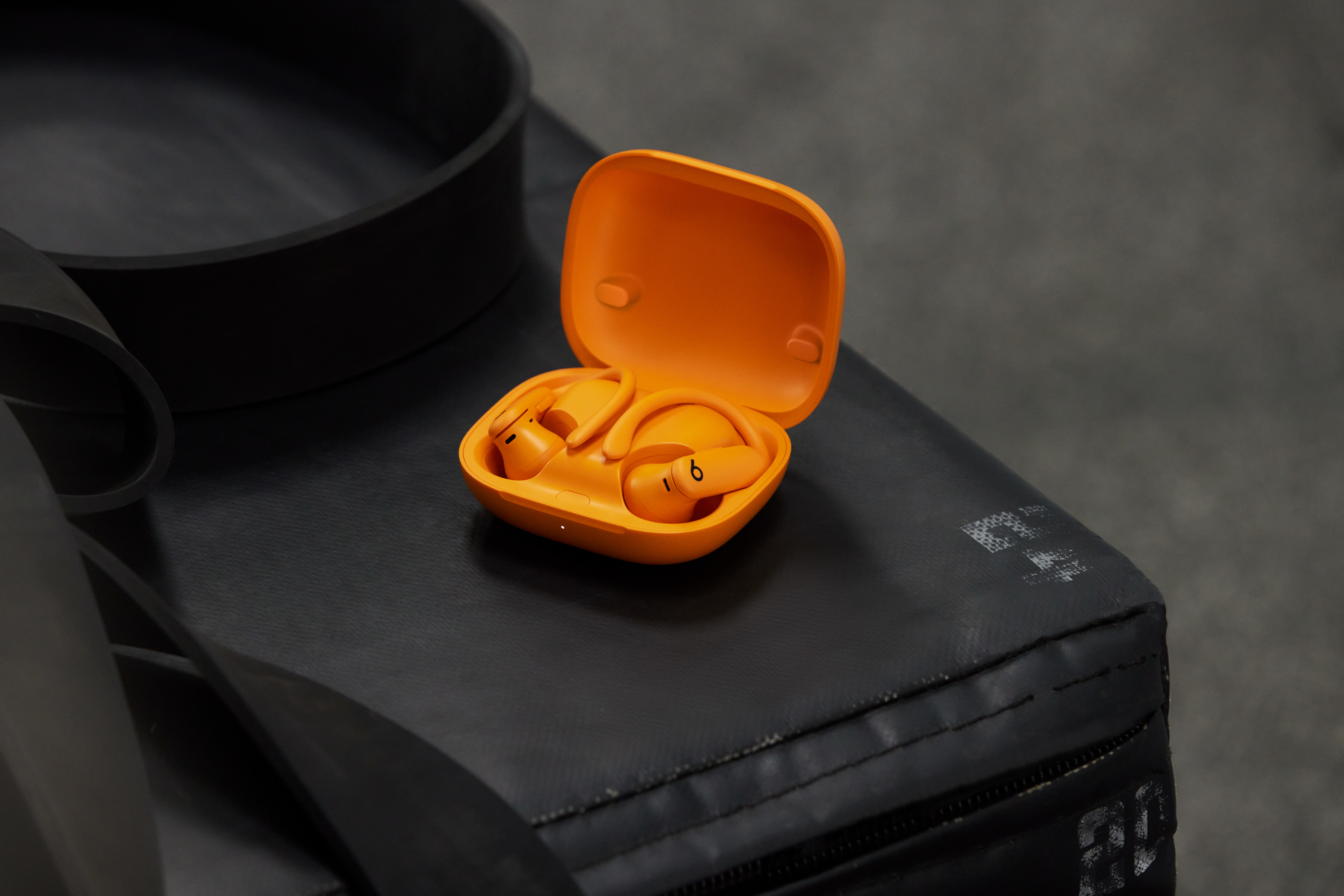Écouteurs oranges dans un étui orange ouvert sur surface noire.