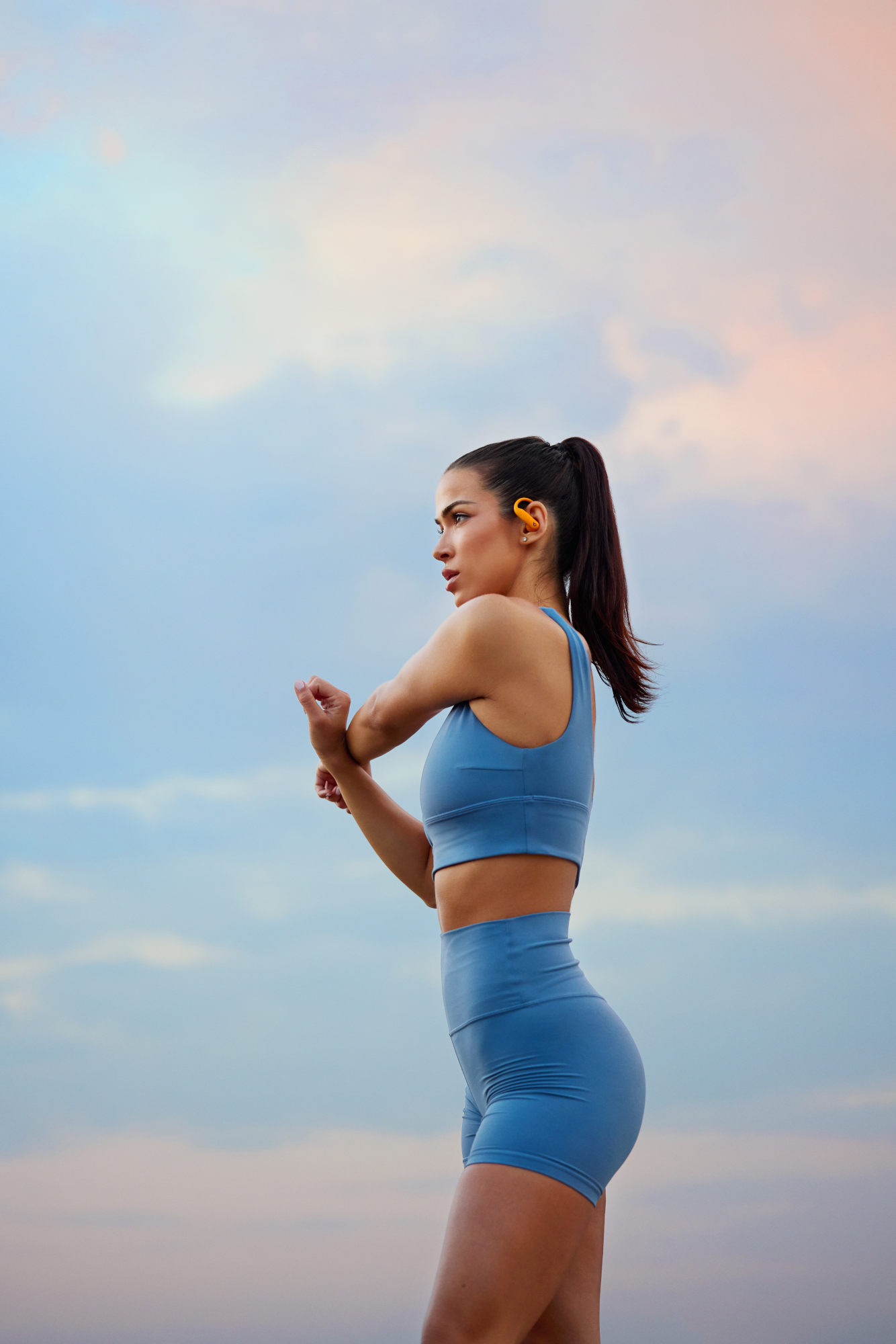Une femme en tenue de sport s'étirant à l'extérieur.