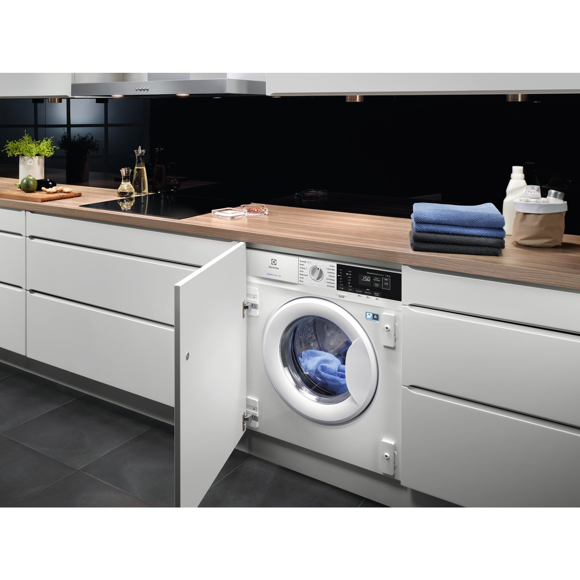 Una lavadora integrada blanca con la puerta abierta en un entorno de cocina moderno.