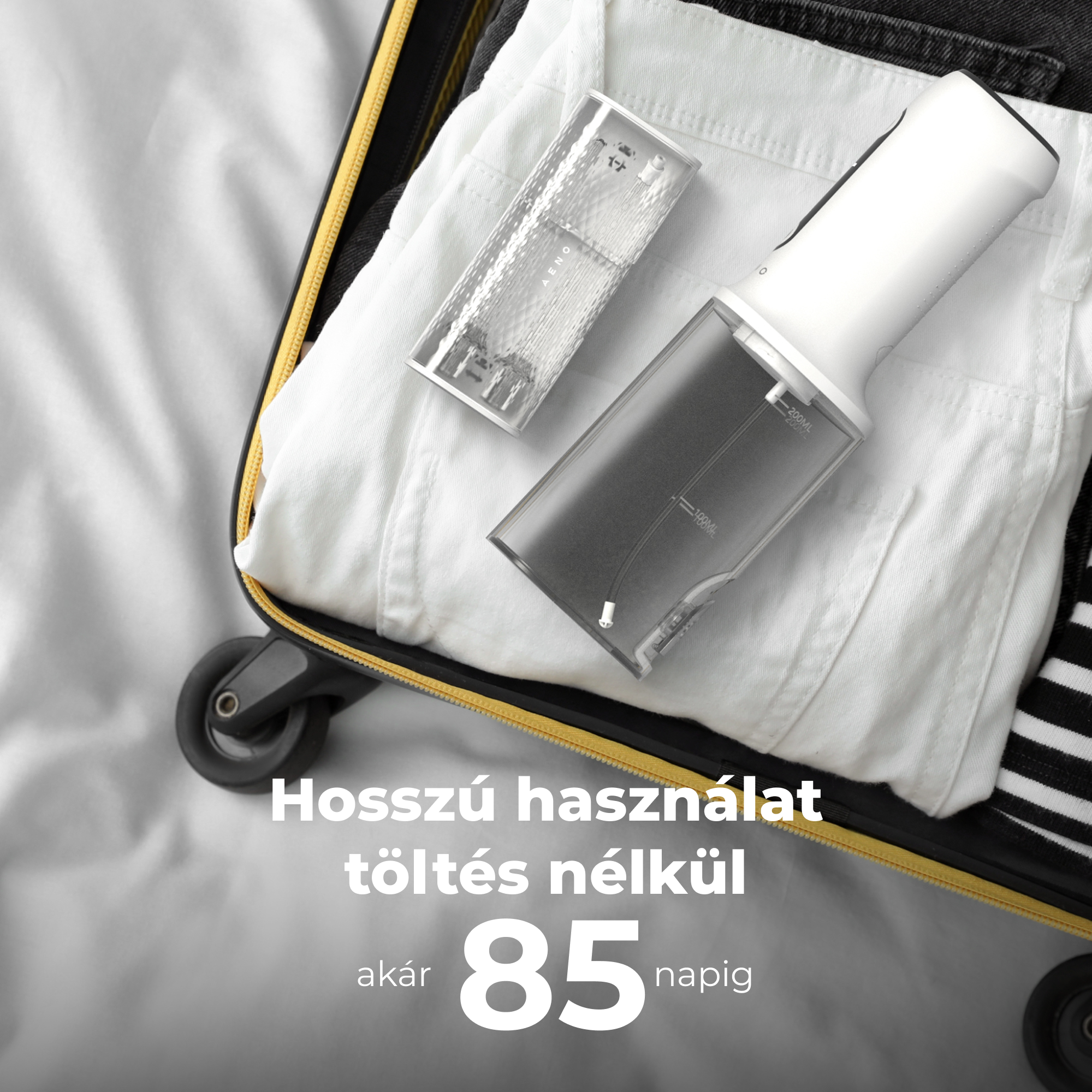 Fehér-fekete bőrönd nyitva, fehér inggel és egy eszközzel benne. Világos háttér.