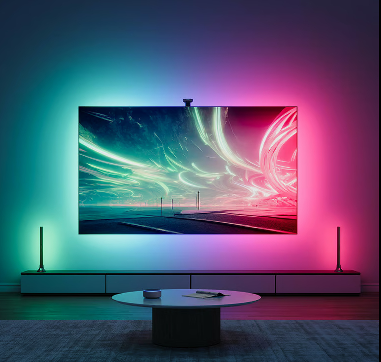 Telewizor z neonowym oświetleniem. Stół i dwie lampy na pierwszym planie.