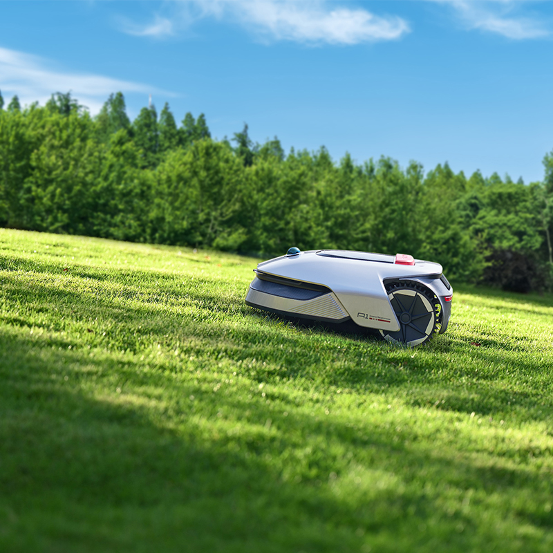 Mavi gökyüzü altında yeşil çimlerde robot çim biçme makinesi.