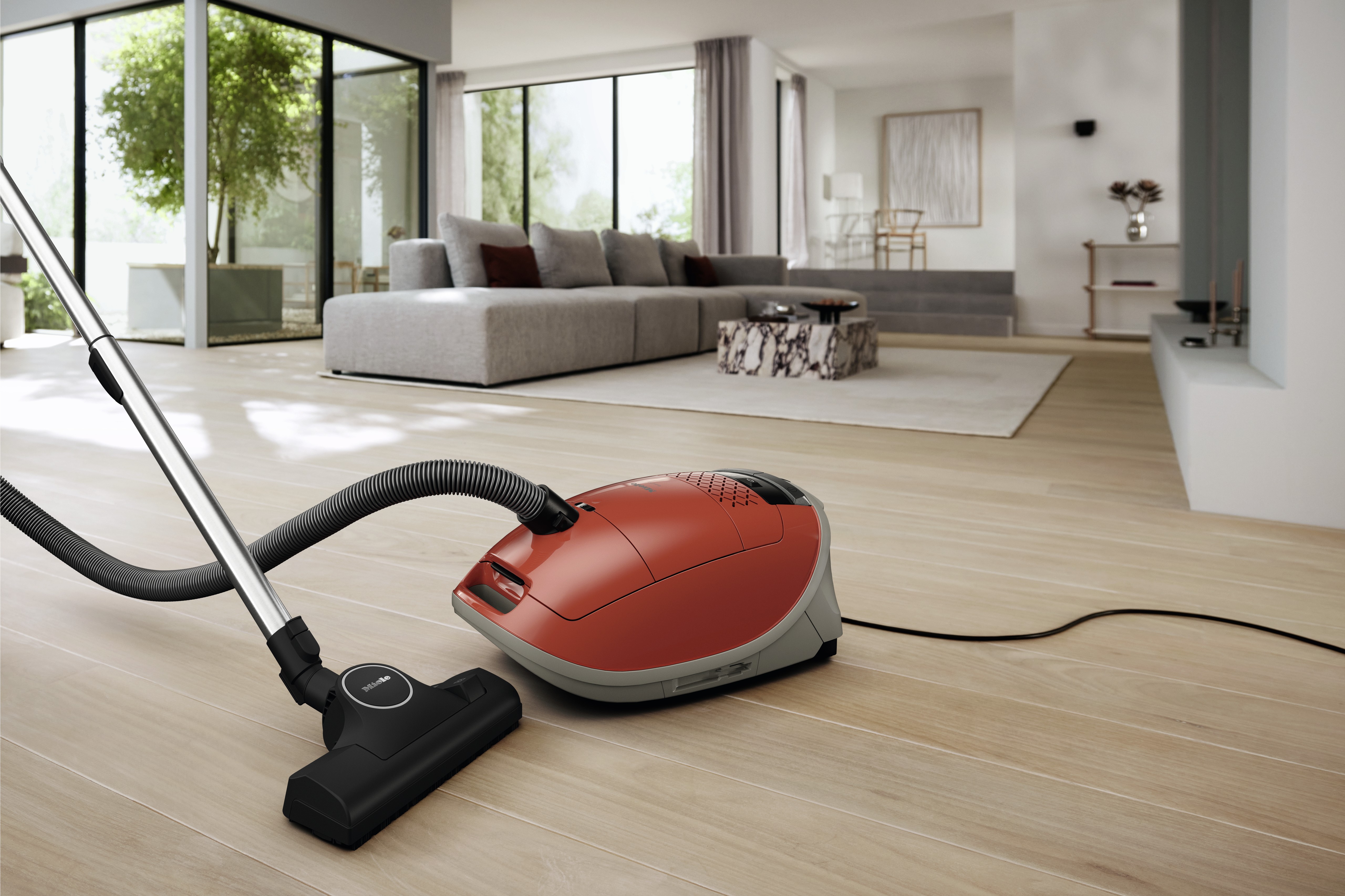 Roter Staubsauger auf Holzboden in einem modernen Wohnzimmer.