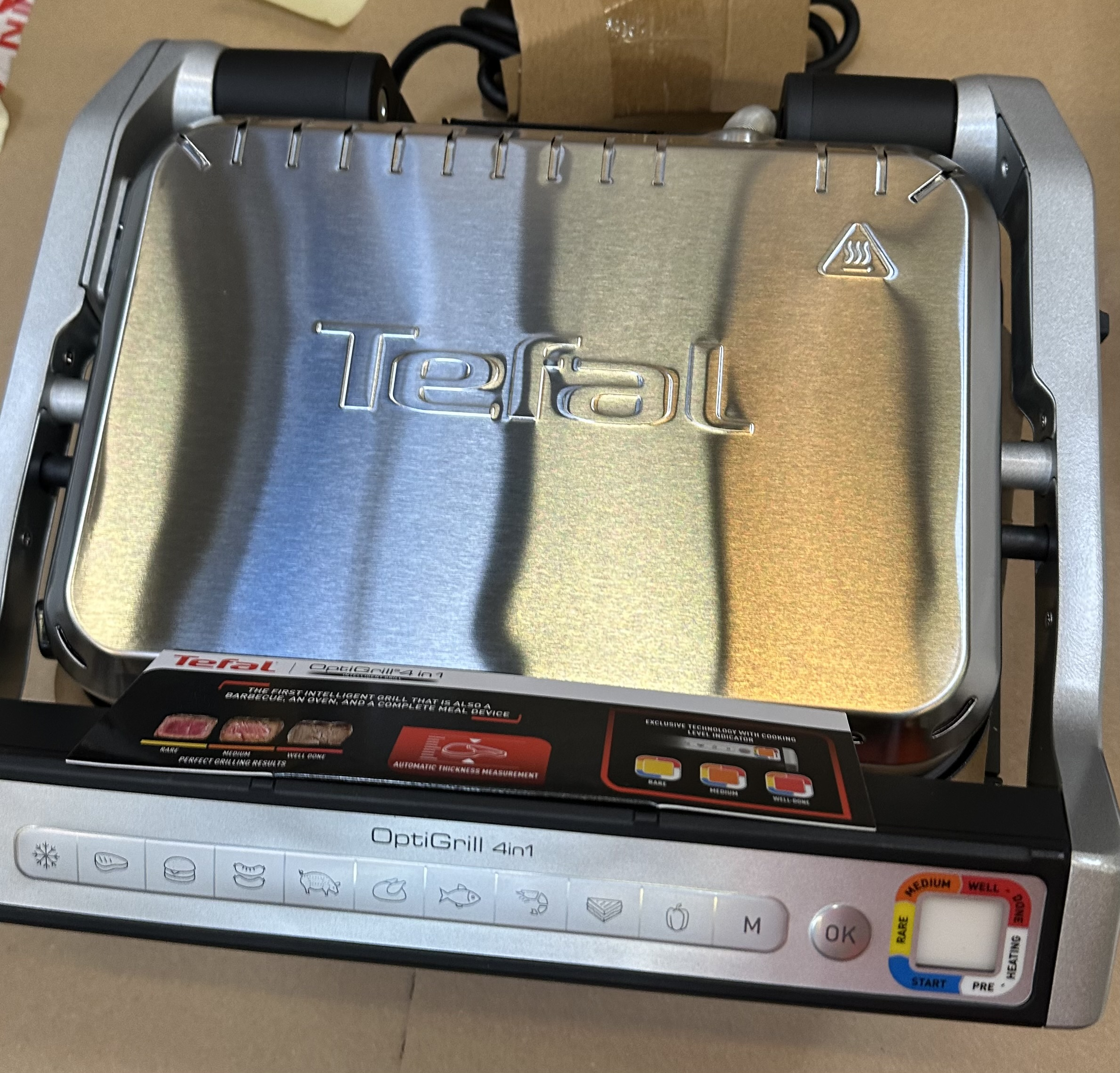 Tefal OptiGrill 4w1, srebrny grill z panelem sterowania. Grill jest otwarty.