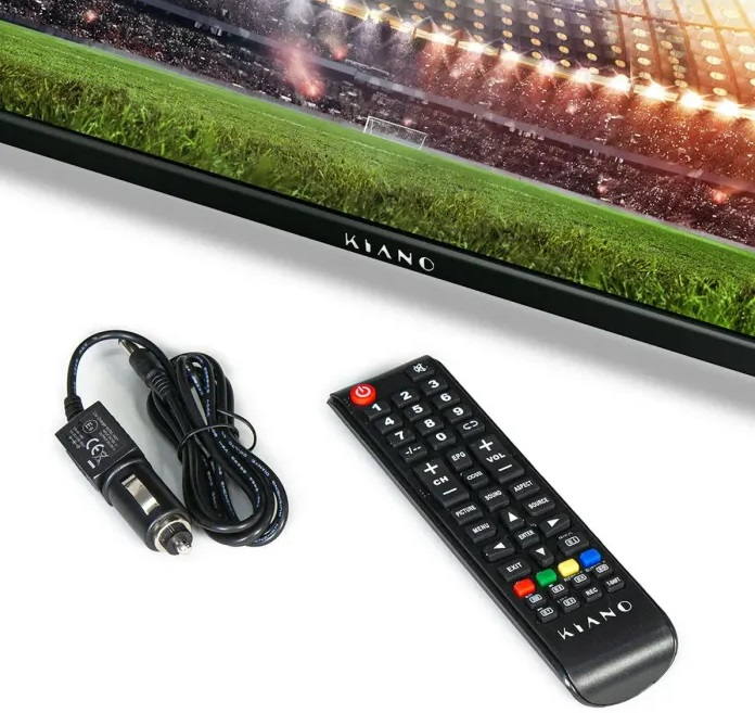 Telewizor Kiano z pilotem i ładowarką samochodową. Telewizor pokazuje stadion piłkarski.