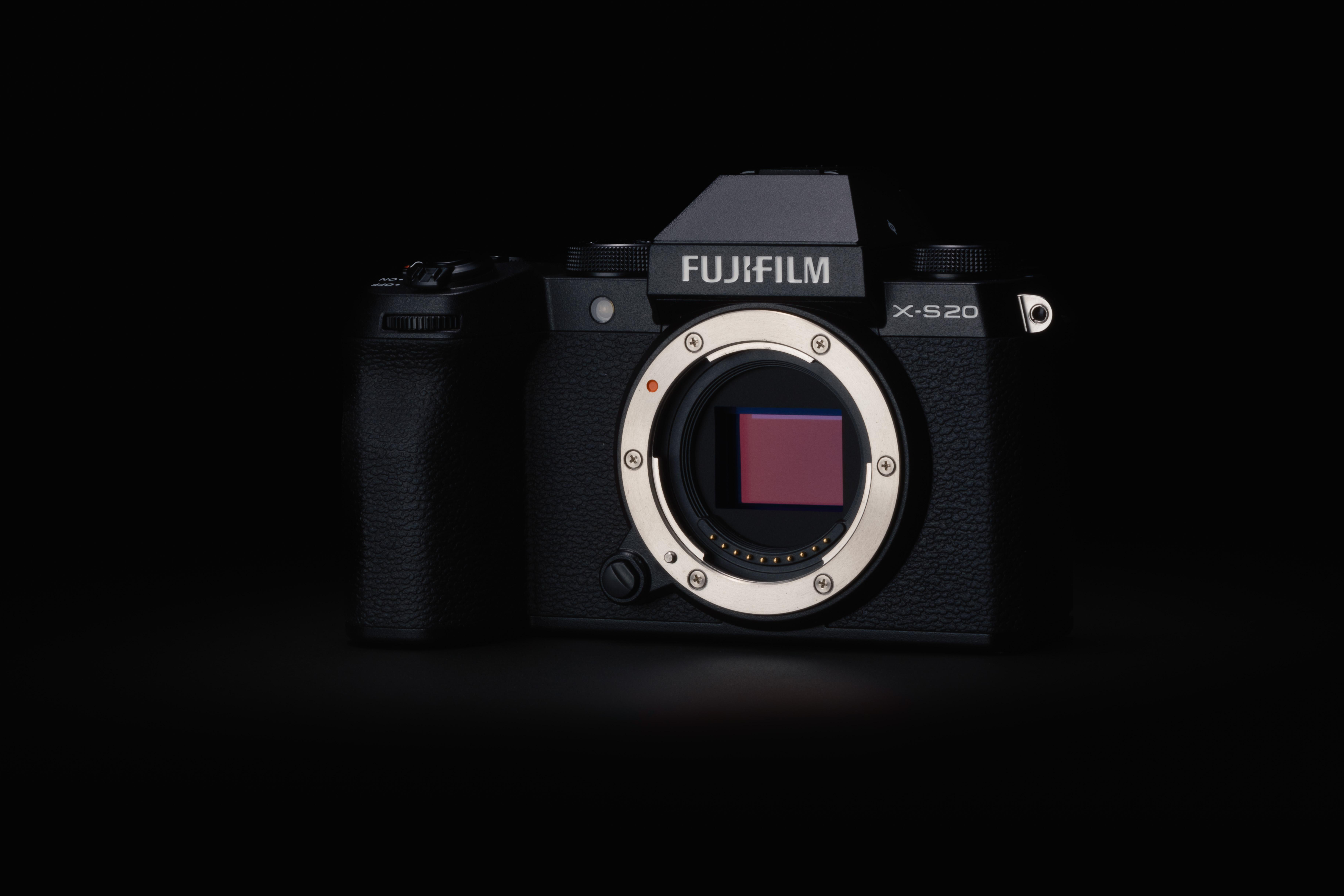 Appareil photo Fujifilm X-S20 noir centré sur fond sombre, montrant les détails de l'objectif et du corps.