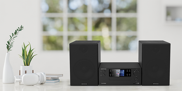 Un sistema stereo Kenwood nero con altoparlanti e cuffie su una superficie bianca.