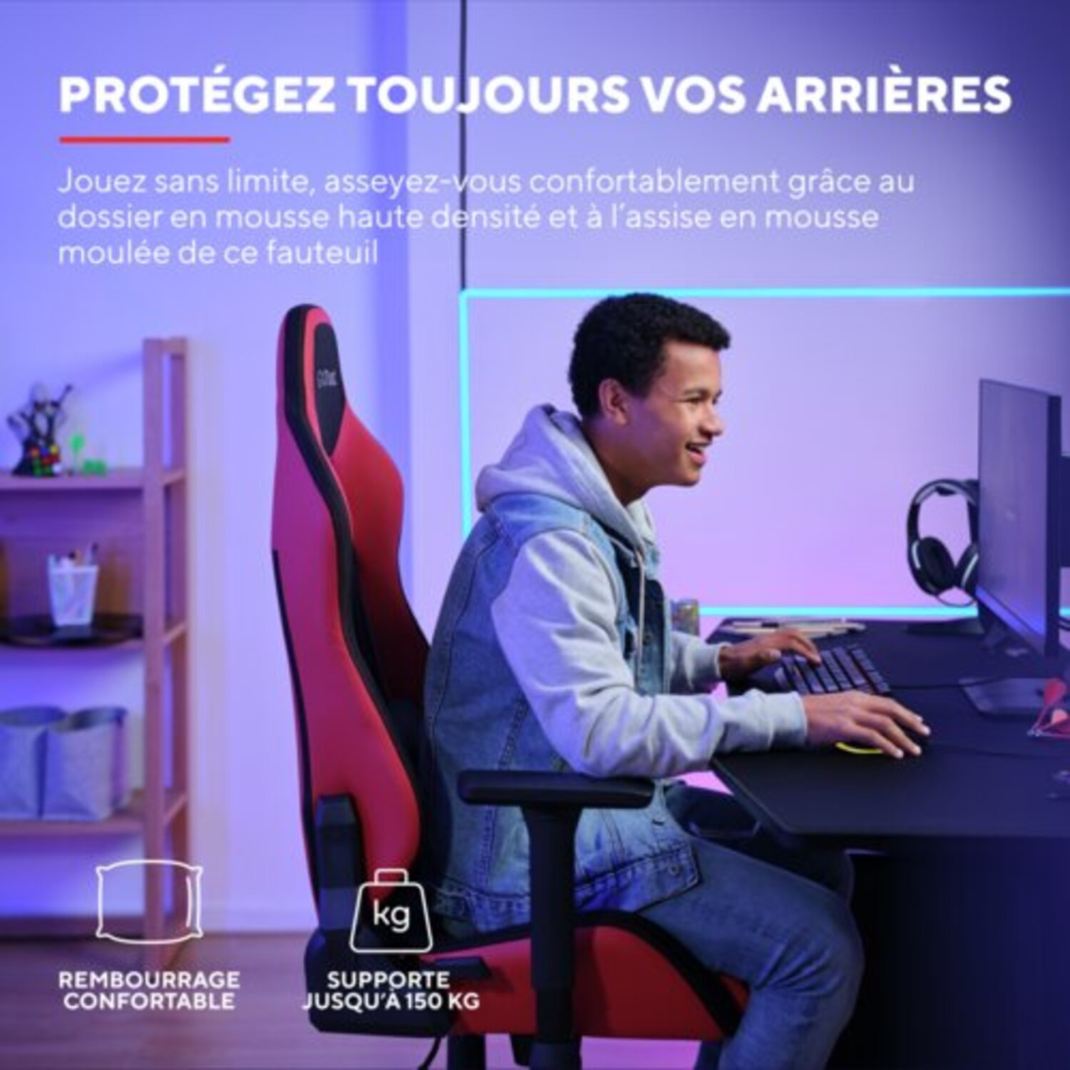 Homme jouant dans une chaise rouge et noire, avec un moniteur, un clavier et une souris sur un bureau noir.
