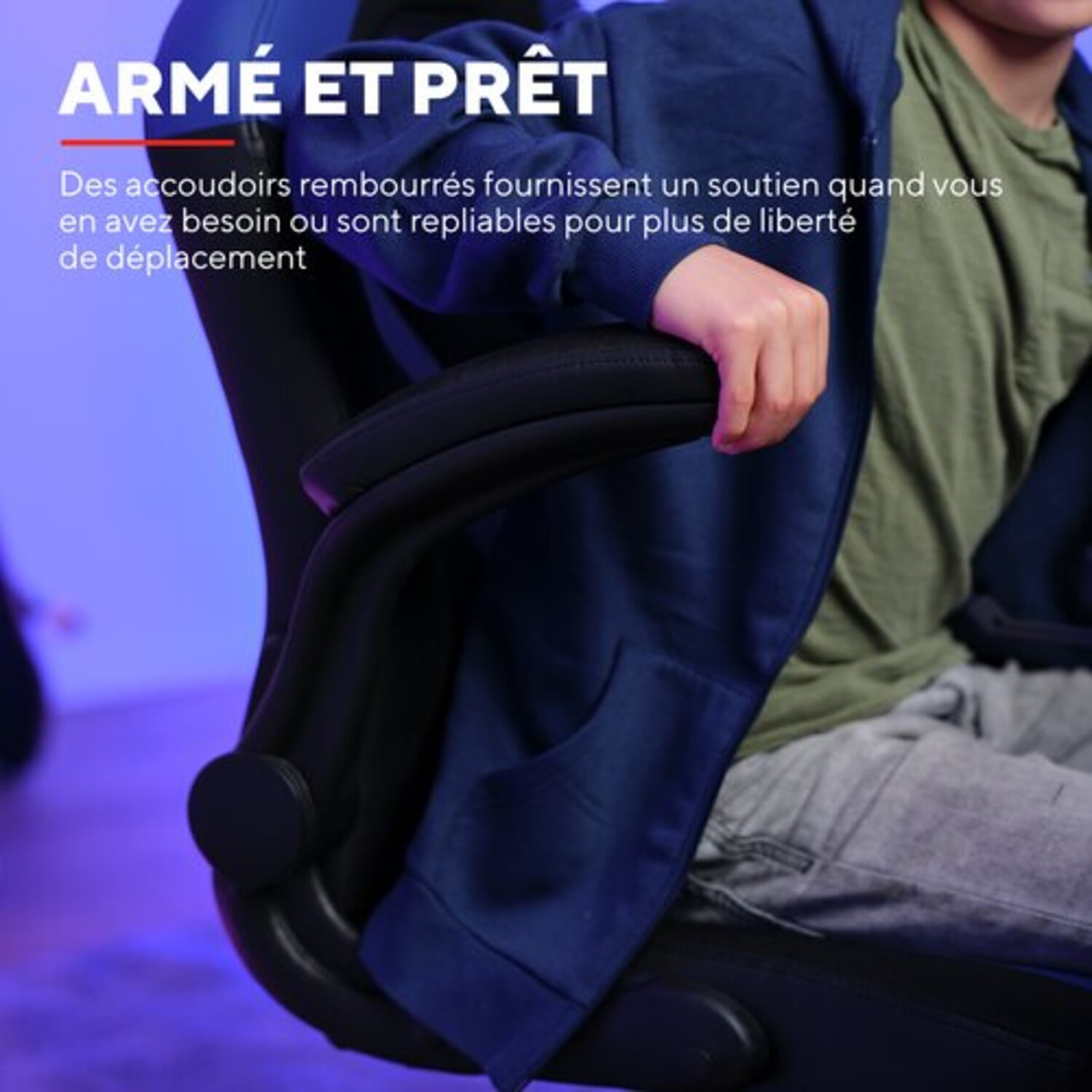 Gros plan sur l'accoudoir du fauteuil de jeu. Veste bleue, accoudoir noir.