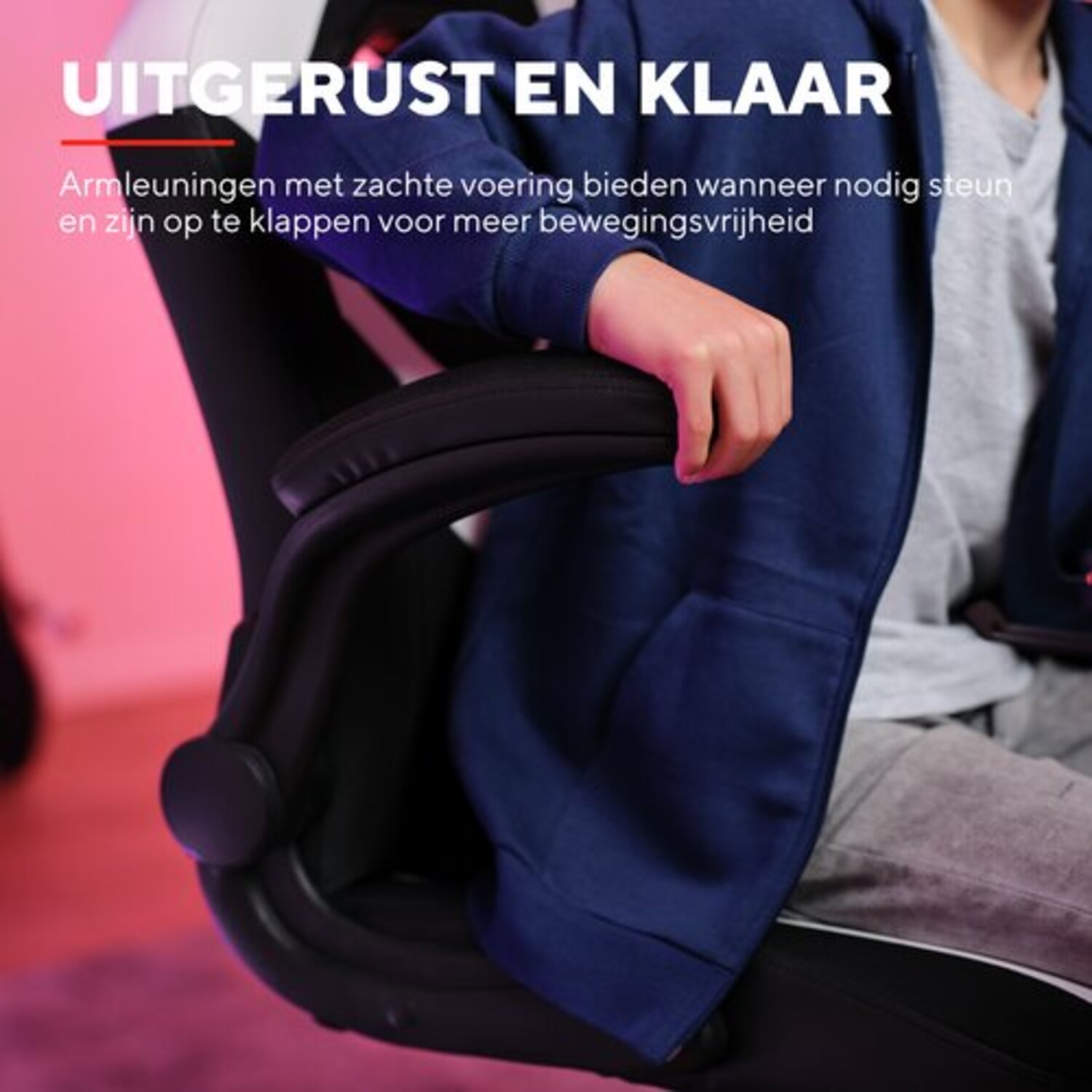 Close-up van een arm in blauwe jas rustend op een zwart-witte gamingstoel armleuning. Tekst: gewatteerde armleuningen.