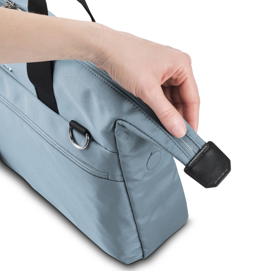 Hand berührt eine blaue Tasche. D-Ring und Reißverschluss sichtbar, auf weißem Hintergrund.