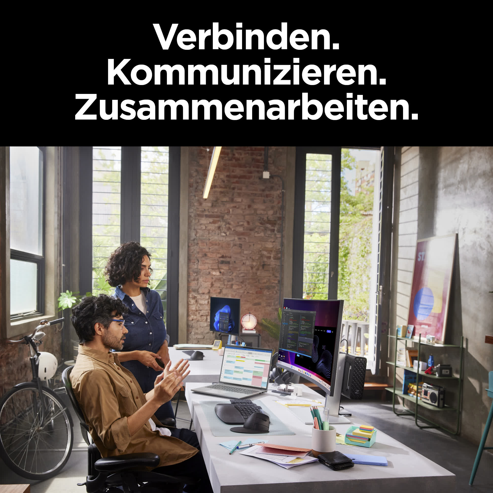 Büroszene mit zwei Personen, die vor einem Computer diskutieren. Text: 'Verbinden. Kommunizieren. Zusammenarbeiten.'