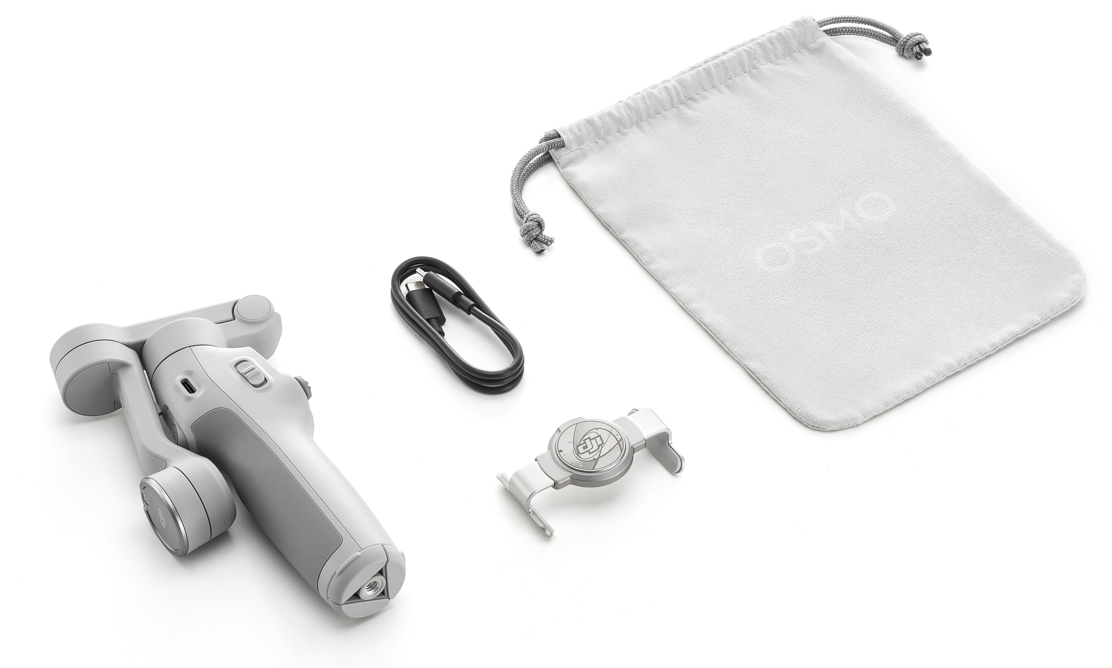 Ręczny gimbal, ładowarka, kabel, uchwyt na telefon i torba na białej powierzchni.