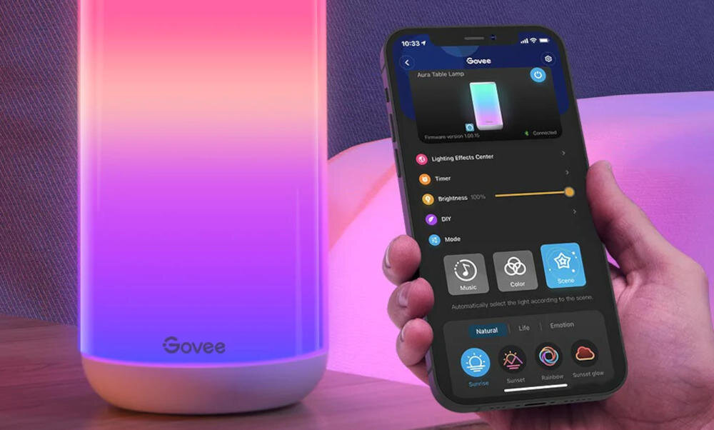 Dłoń trzymająca telefon z interfejsem aplikacji Govee i zmieniającą kolory lampą w tle.