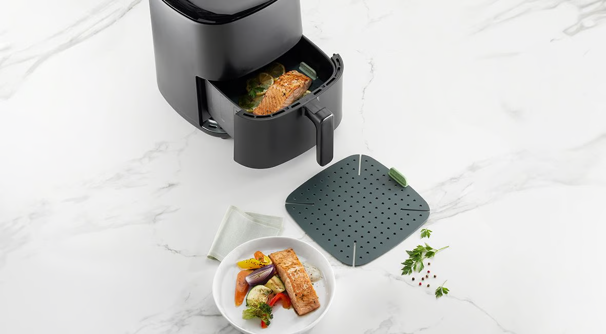 Eine Heißluftfritteuse mit Griff, Deckel und einem quadratischen Grill.