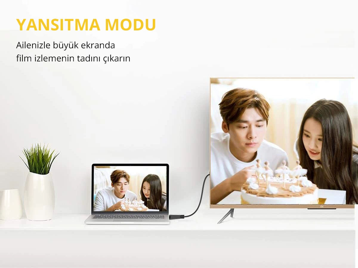 Pasta bağlı insanları gösteren bir dizüstü bilgisayar, bir TV'ye bağlı. Bitkili beyaz masa.