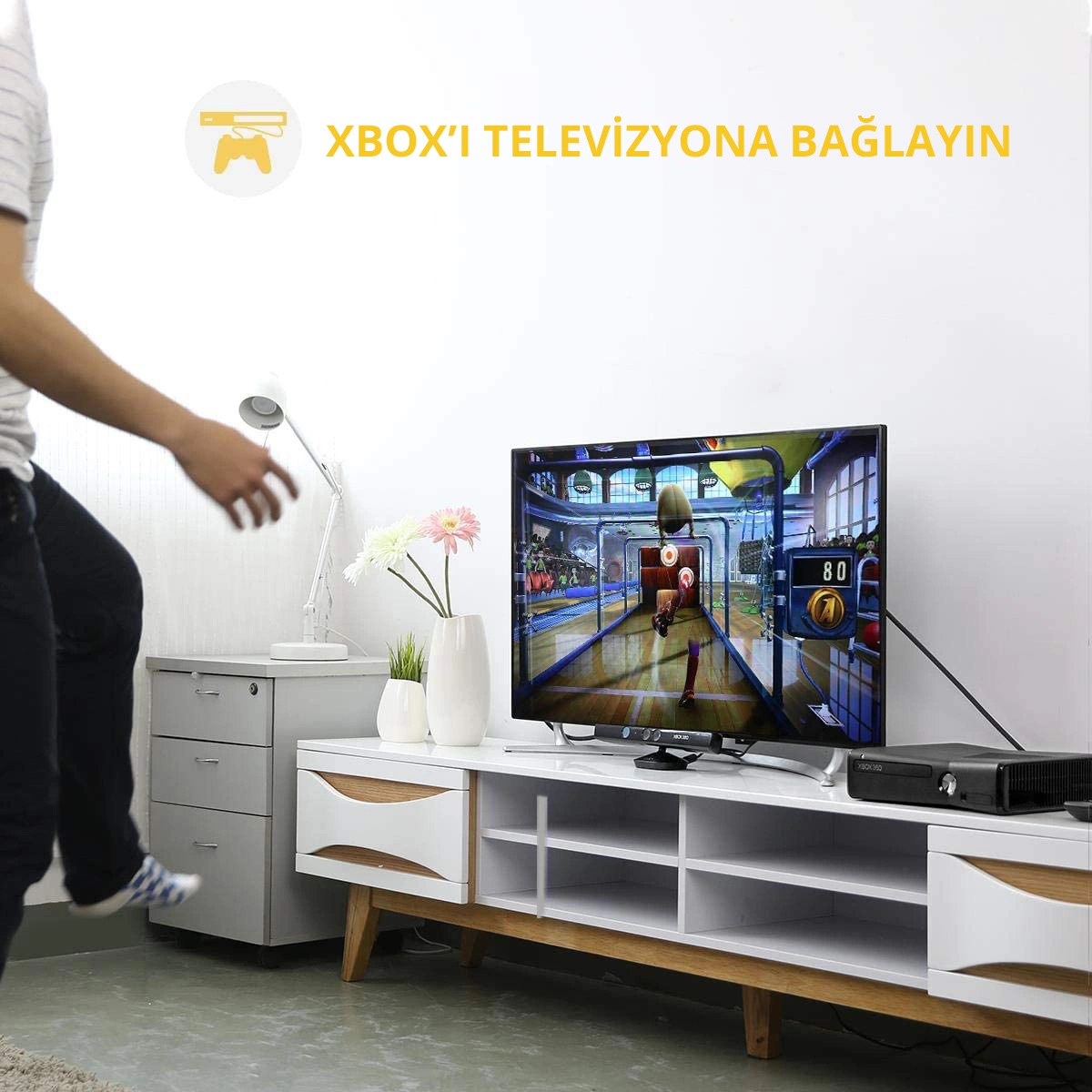 Bir kişi, bir oyun görüntüleyen bir TV ekranına doğru yürüyor. Metin: Xbox'ı TV'ye bağlayın.