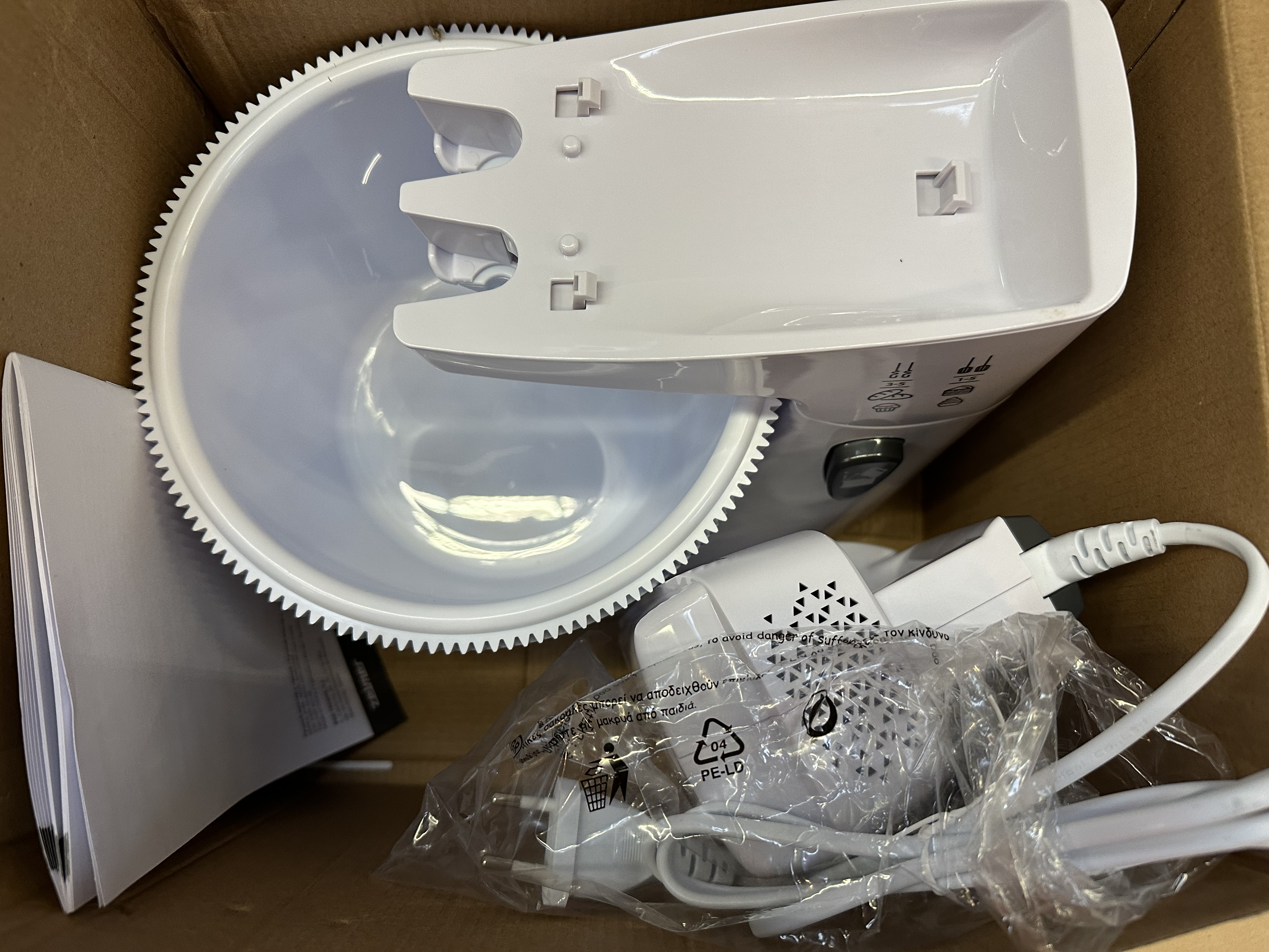 Białe urządzenie kuchenne zdemontowane w kartonowym pudełku.