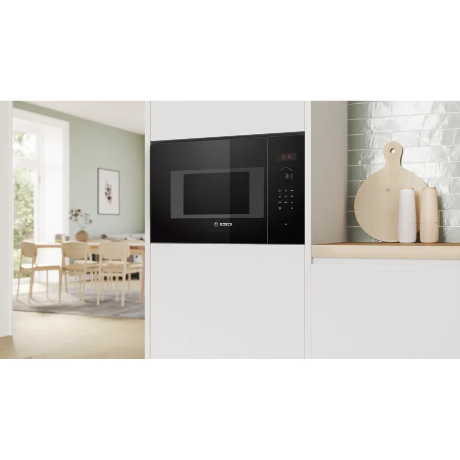 Black microwave oven in a white kitchen cabinet, displaying time. Kitchen scene with a dining area.