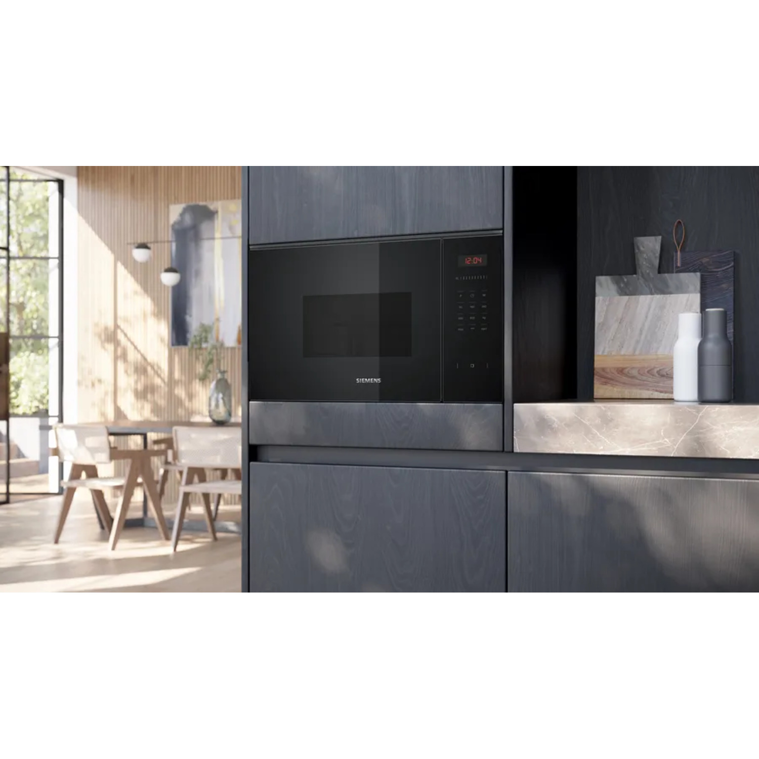 Black built-in microwave oven in a dark kitchen. A dining table and window are visible in the background.