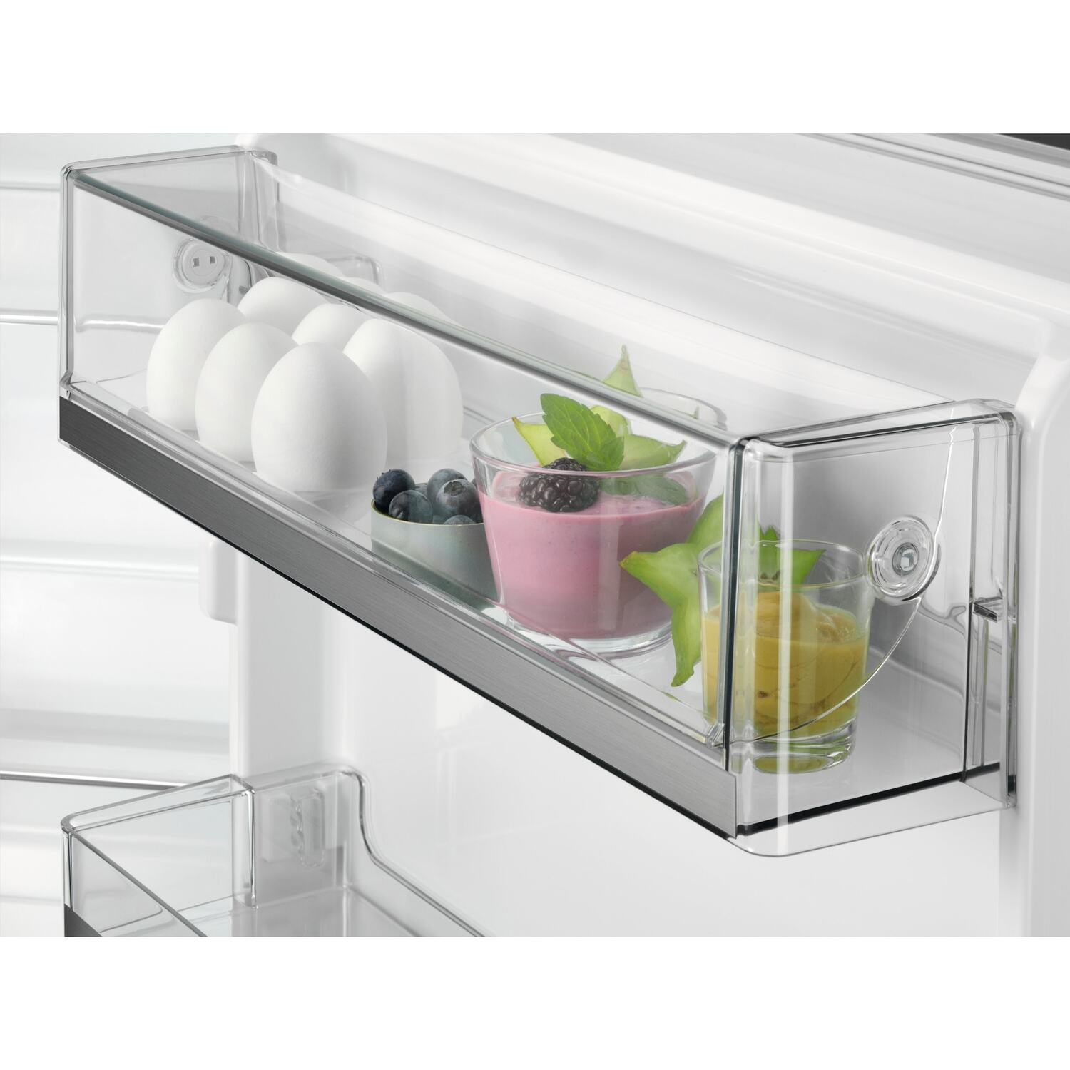 Koelkastinterieur, doorzichtige lades met eten: eieren, smoothies en fruit.