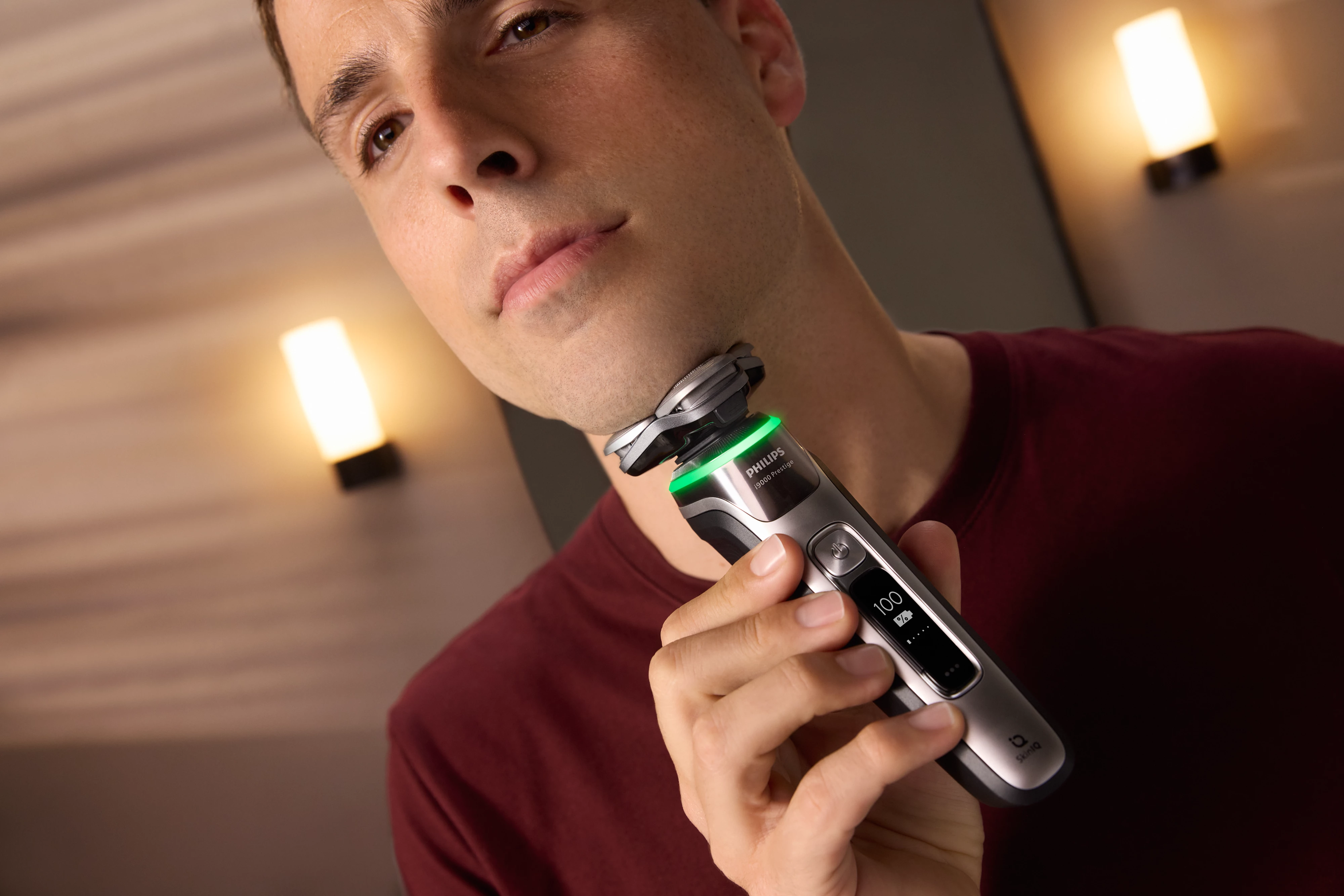 Un uomo si rade il viso. Tiene un rasoio elettrico. Il rasoio è a fuoco, con un display digitale.