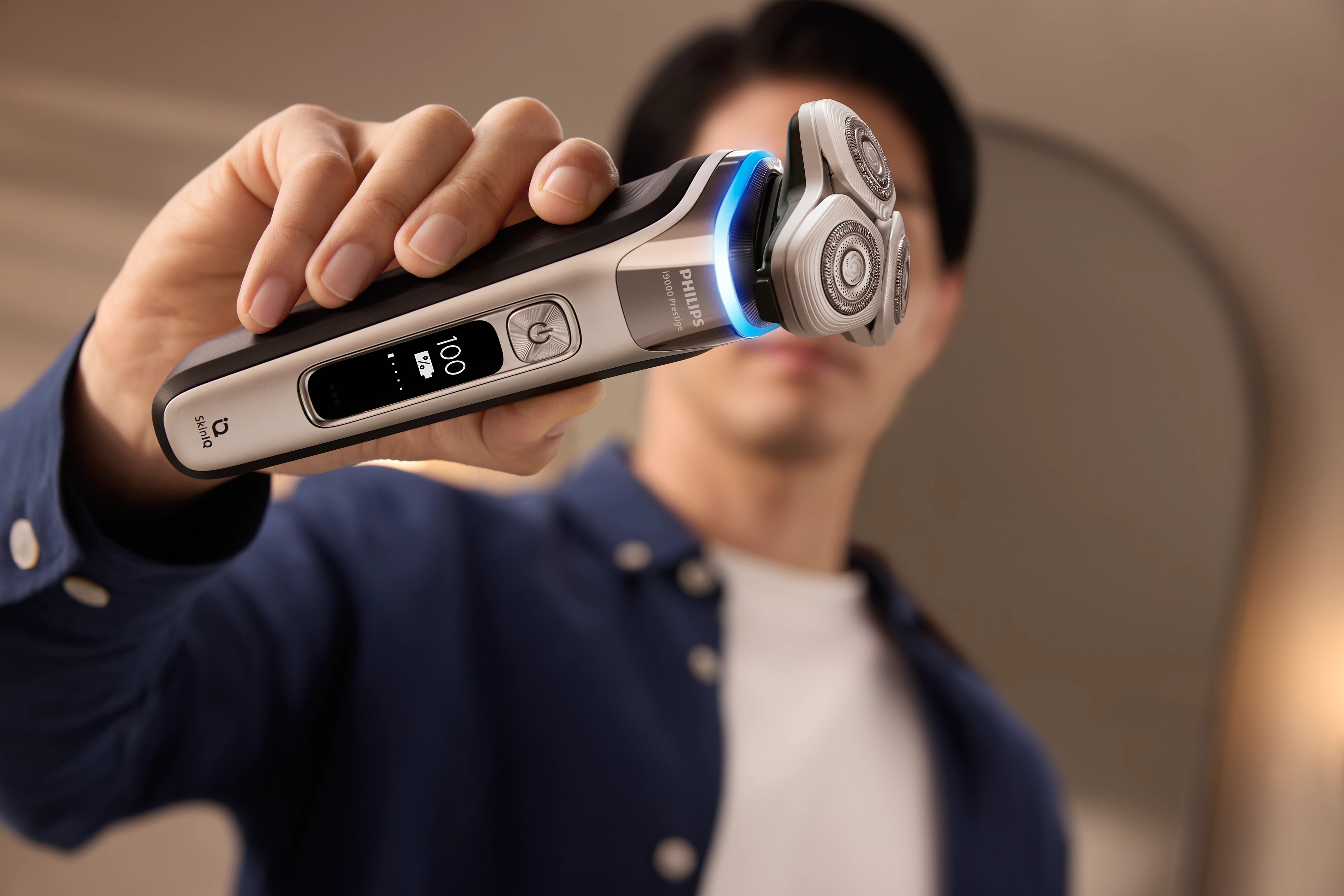 Un uomo tiene un rasoio elettrico. Il rasoio ha un display digitale. Lo sfondo è sfocato.
