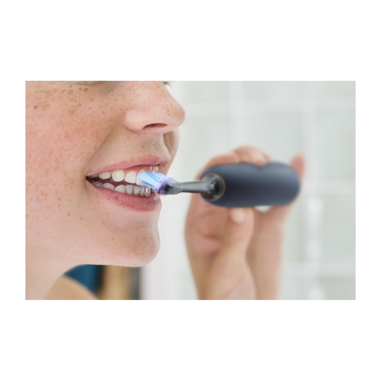 A woman brushing her teeth with a blue-bristled electric toothbrush, close-up view.