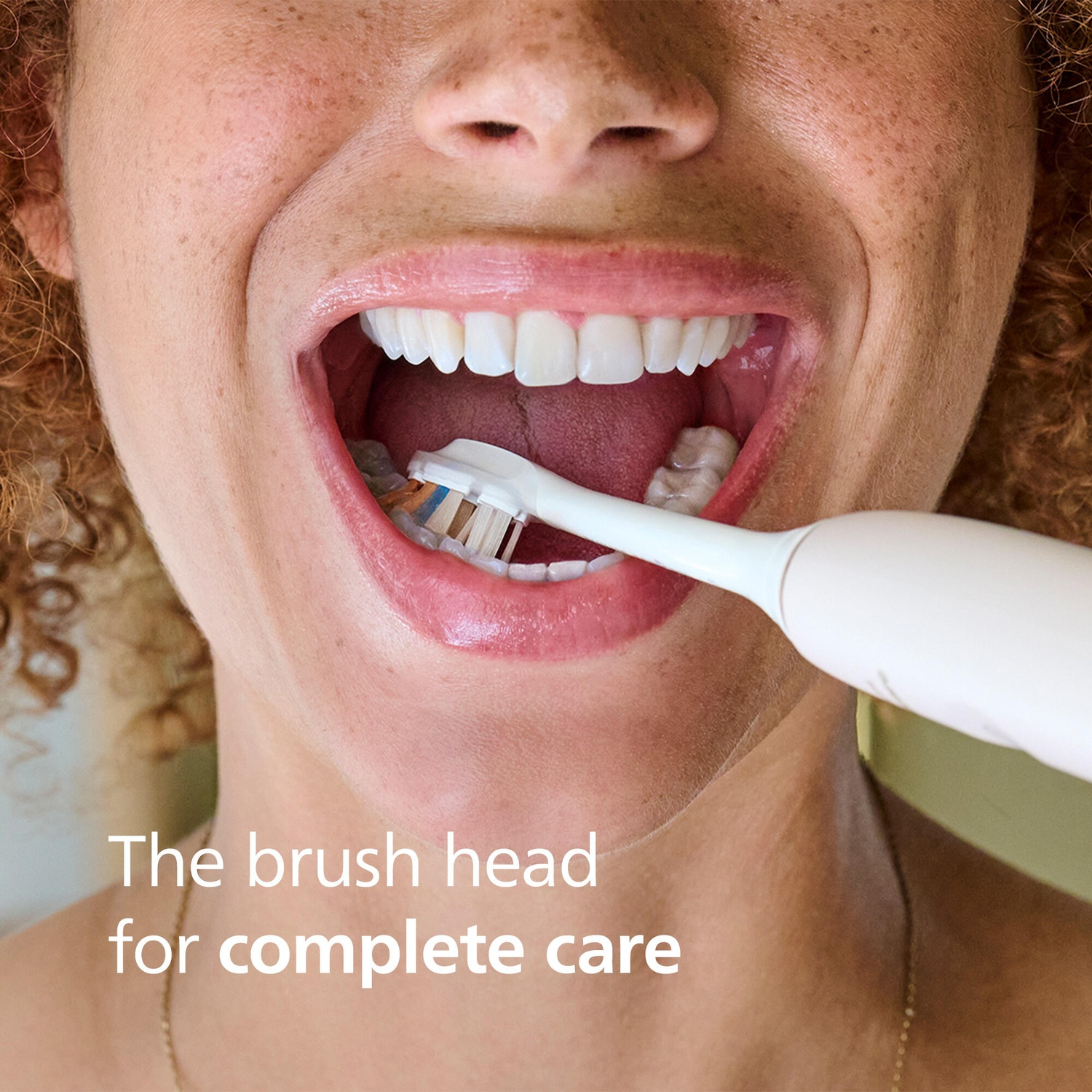 Une personne se brosse les dents avec une brosse à dents électrique blanche.