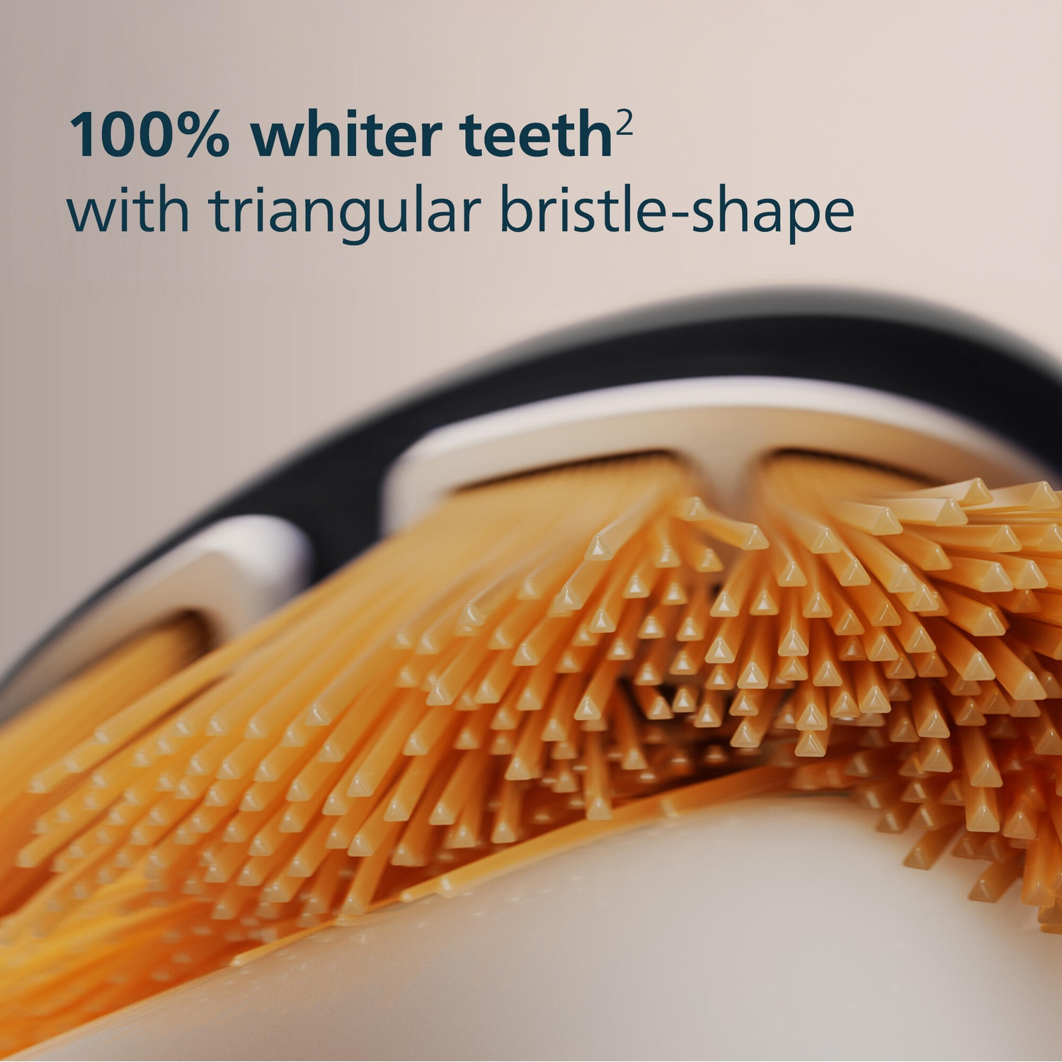 Close-up of a toothbrush head. Text overlay: 100% whiter teeth with triangular bristle-shape.