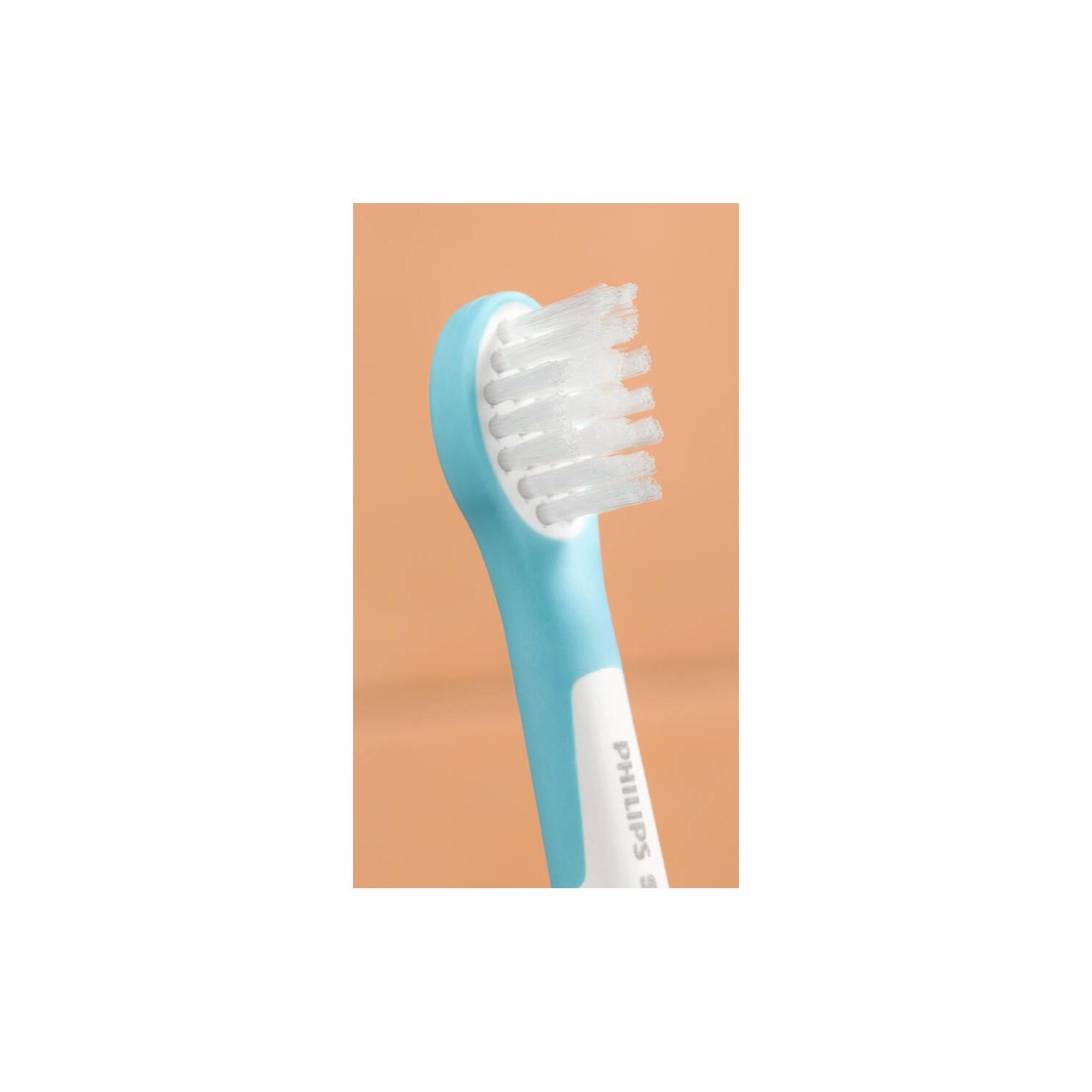Close-up of a blue toothbrush head. White bristles are visible. Orange background.