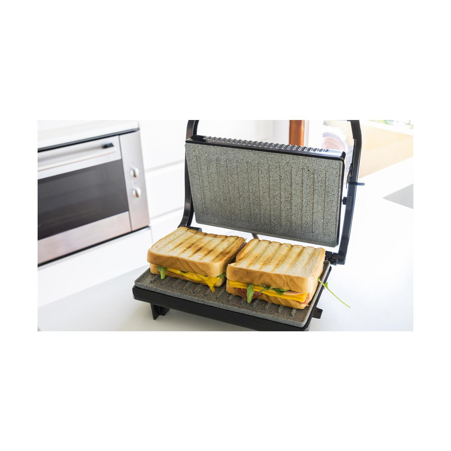 Panini con formaggio su una piastra per sandwich. Sfondo cucina con forno.