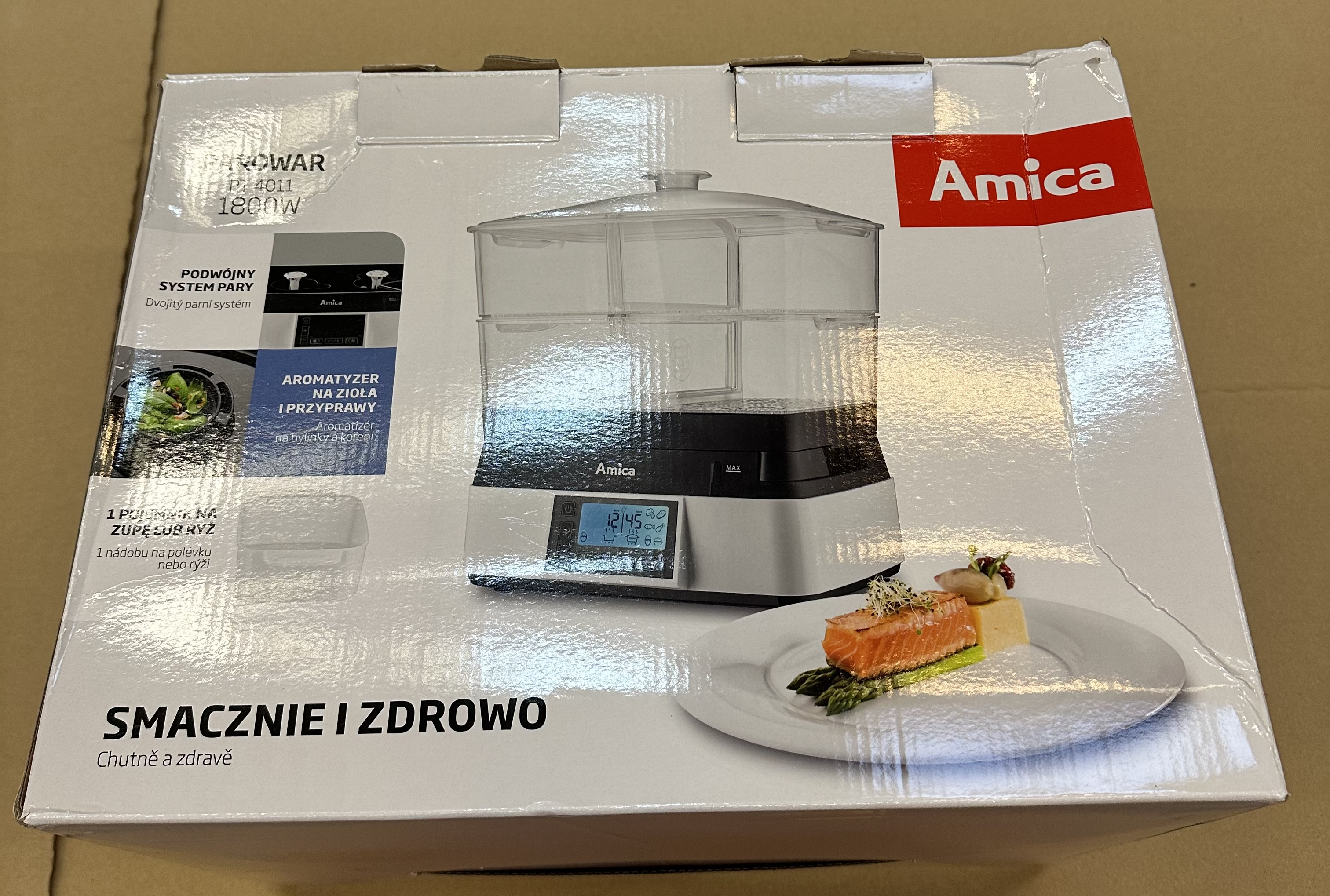 Parowar Amica z dwoma poziomami, cyfrowym wyświetlaczem i daniem z łososiem i szparagami.