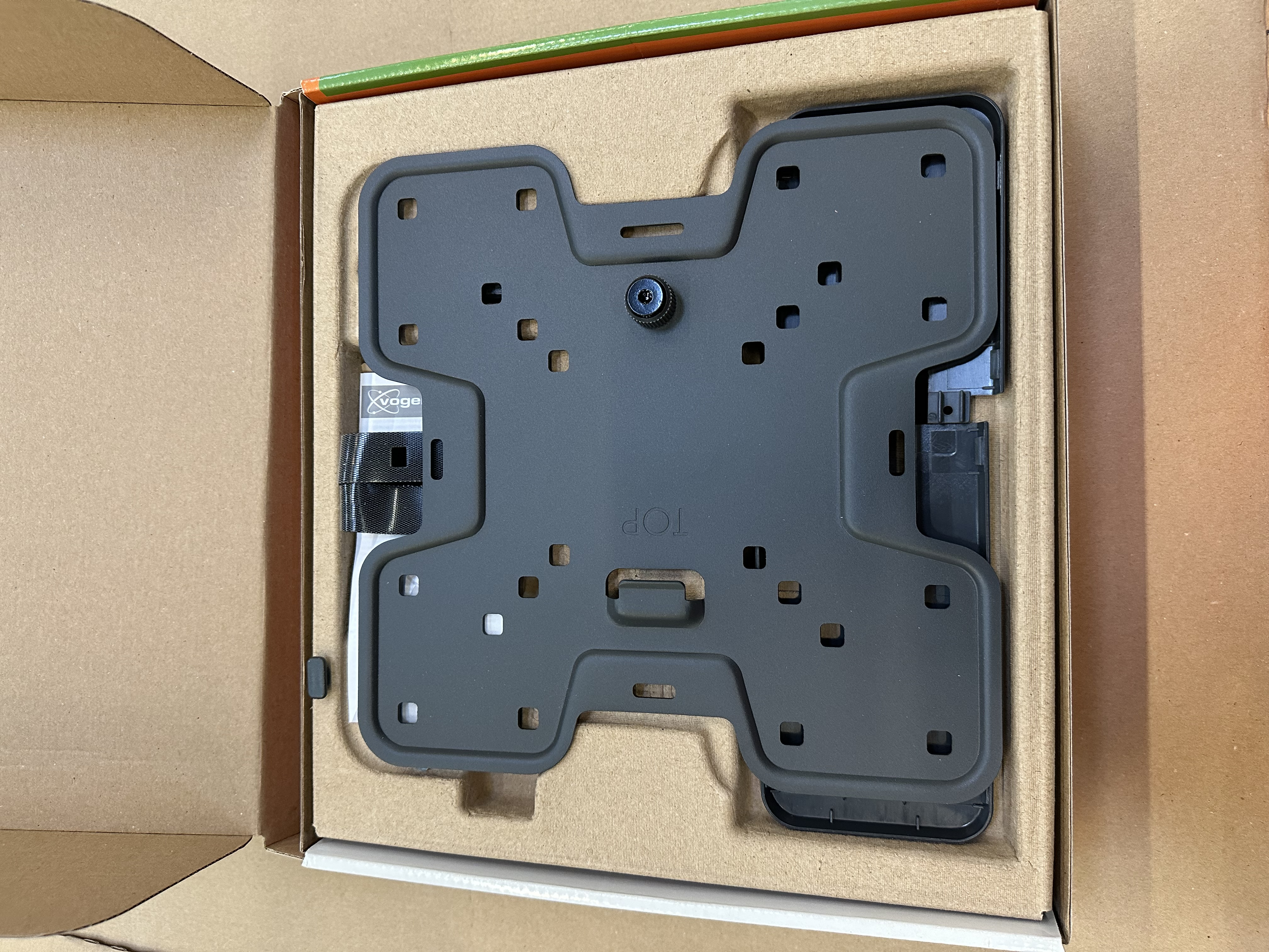 Ciemnoszary wspornik montażowy wewnątrz kartonowego pudełka.