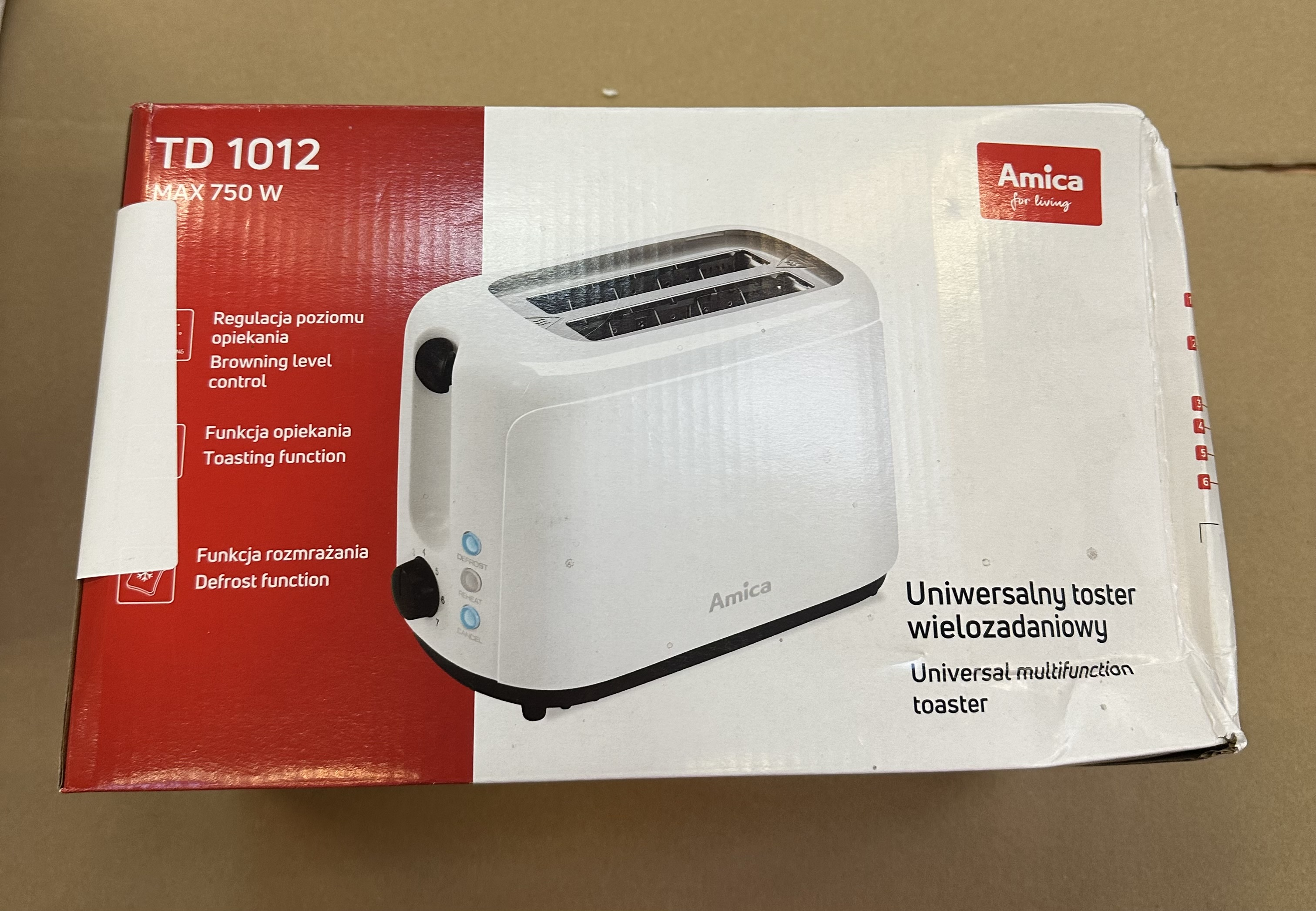 Biały toster w czerwono-białym pudełku. Tekst: Amica, TD 1012, max 750W, Funkcja rozmrażania.