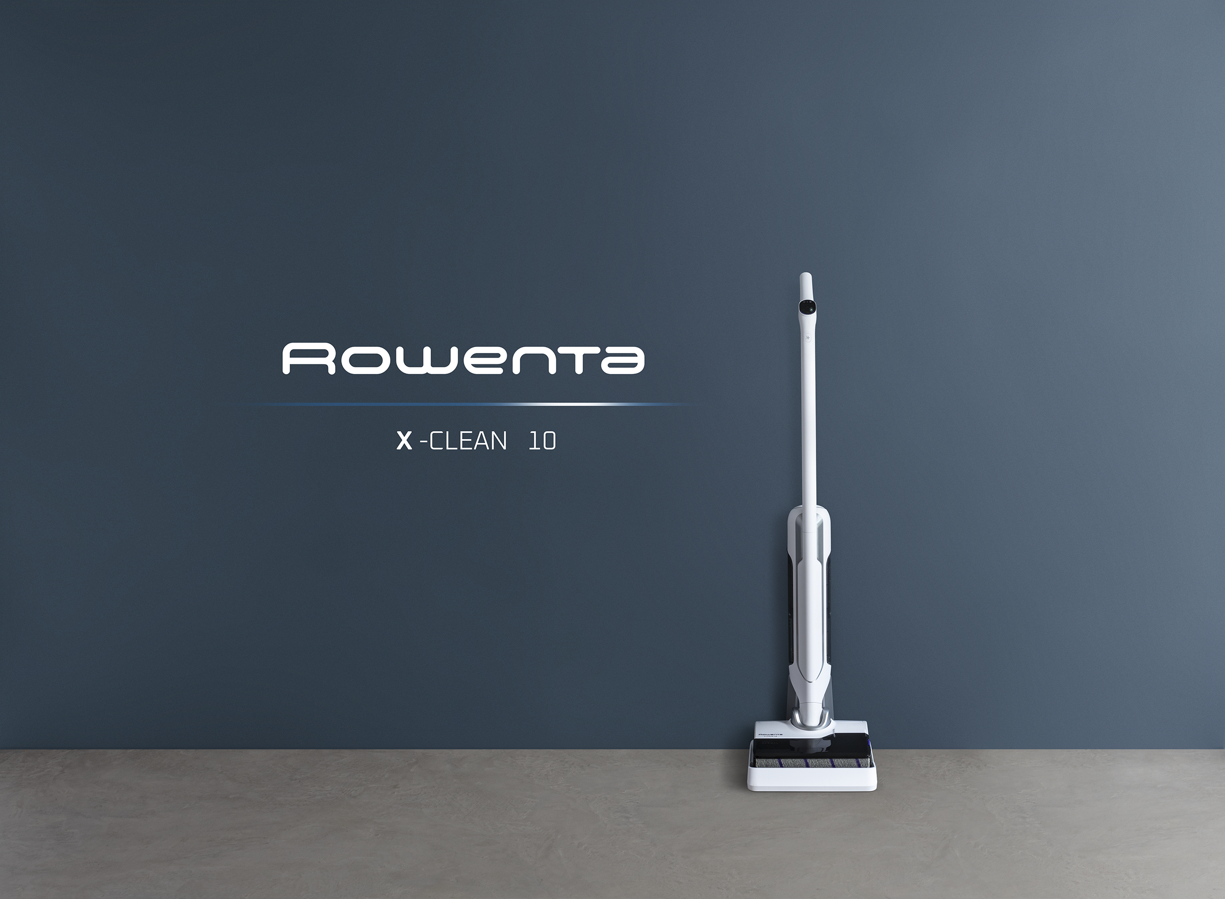 Fehér Rowenta X-Clean 10 porszívó szürke padlón, sötétkék fal előtt. Látható a Rowenta logó és a termék neve.