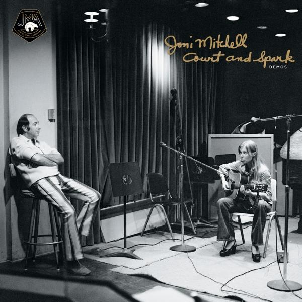Joni Mitchell stúdióban énekel és gitározik. Egy férfi ül a közelben. A falon a felirat: "Court and Spark Demos".