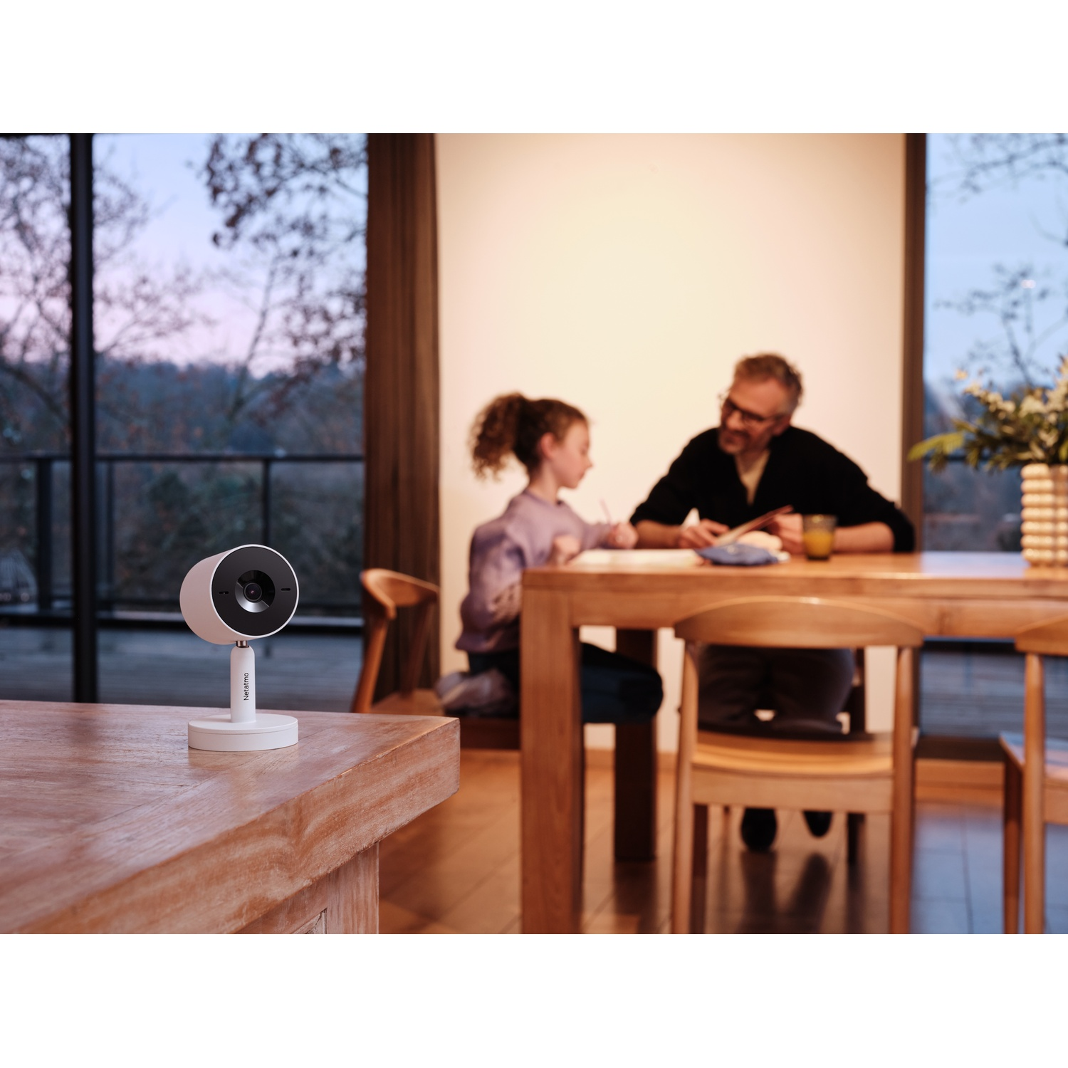 Telecamera di sicurezza su un tavolo di legno, con persone sullo sfondo.