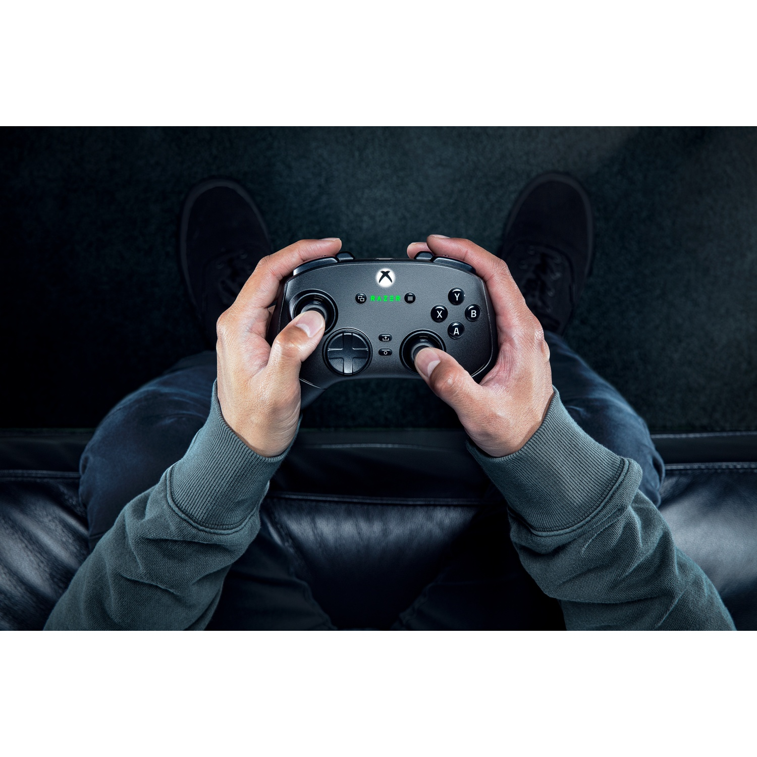 Hands holding a black controller, playing a game. The person is sitting down.