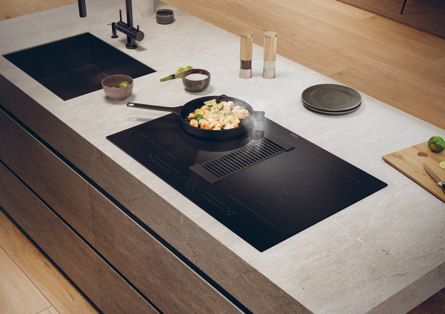 Isla de cocina con placa de cocción negra, comida cocinándose y sistema de ventilación integrado.