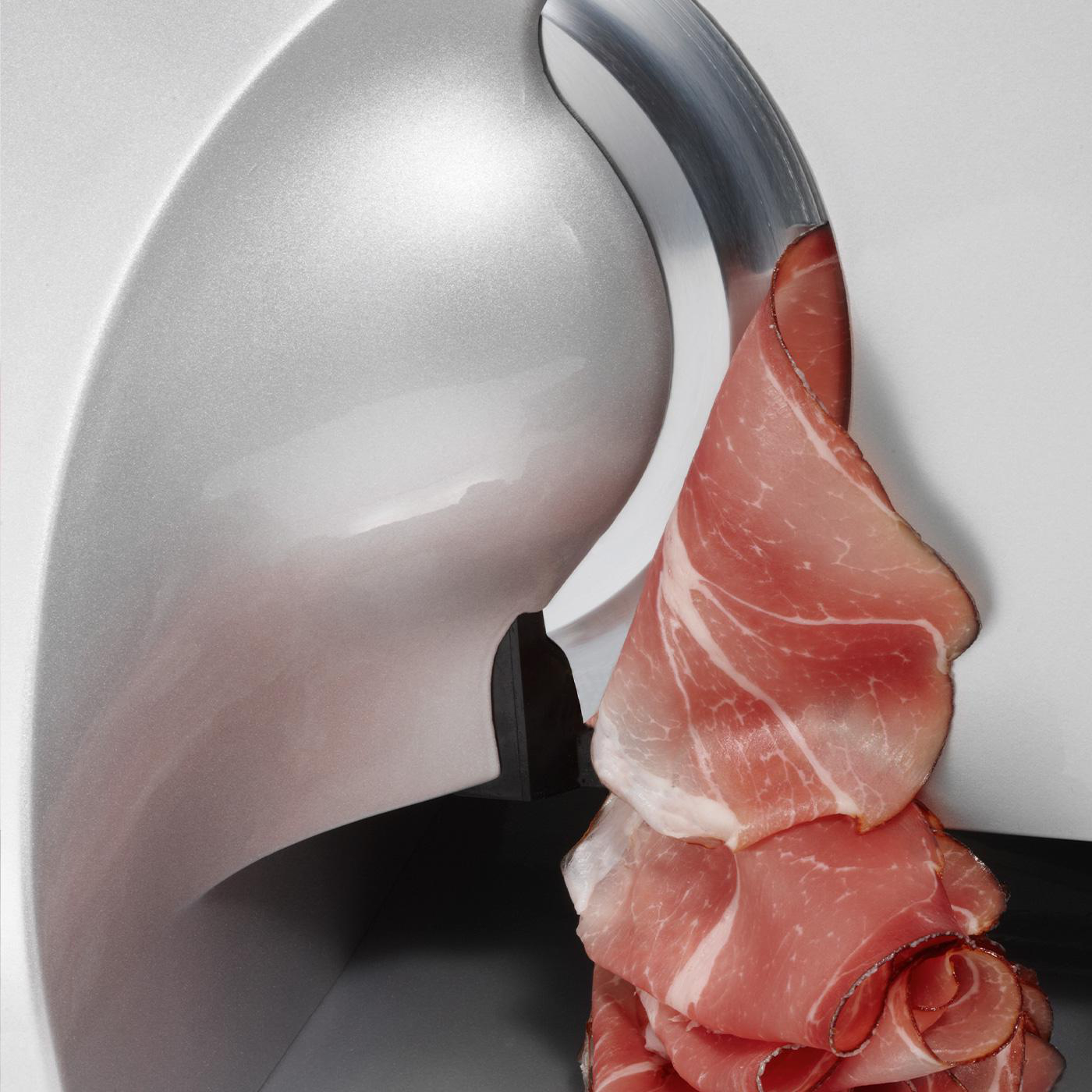 Nahaufnahme eines Fleischschneiders. Geschnittener Prosciutto wird geschnitten. Die Maschine ist silber und weiß.