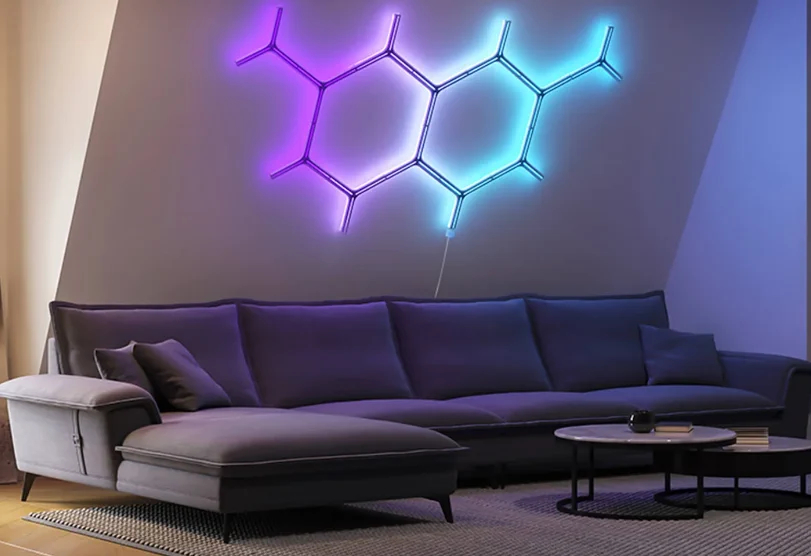 Salon z szarą sofą, dwoma stolikami i neonami w kształcie cząsteczki, fioletowy i niebieski.
