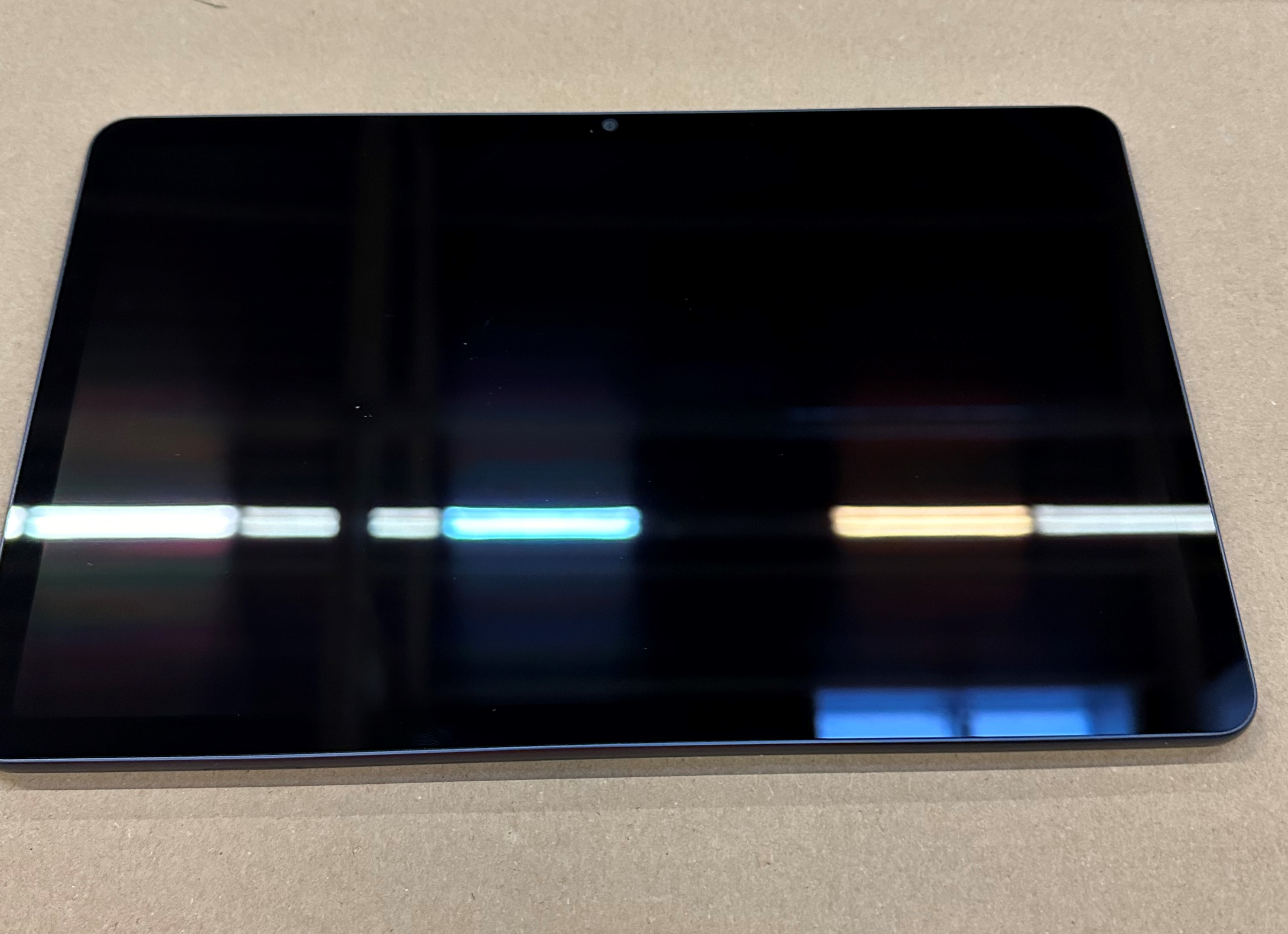 Niebieski tył tabletu z aparatem i białą naklejką.